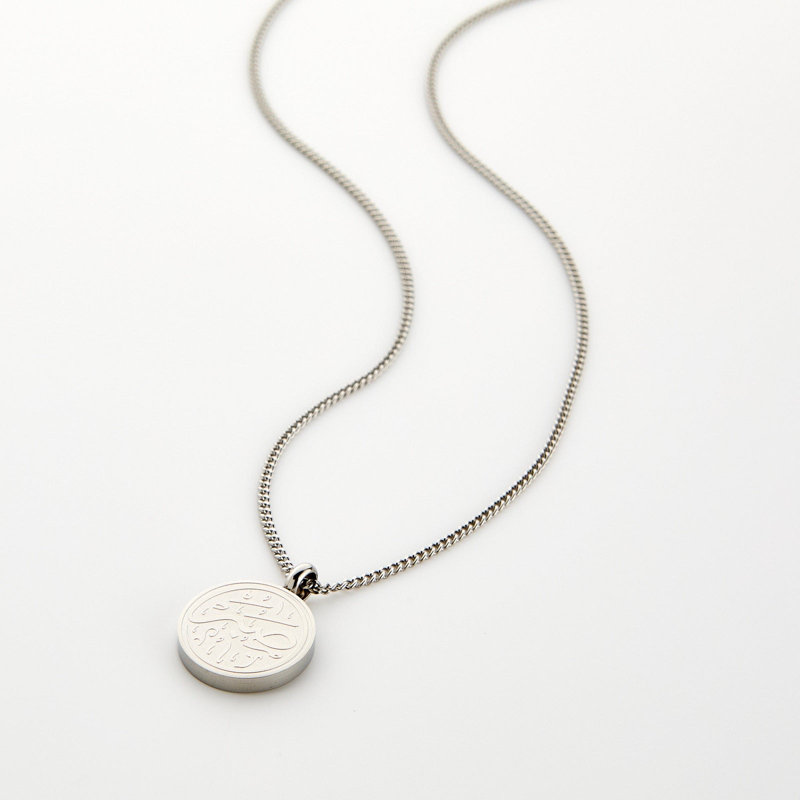 Silver necklace with a circular 'Sabr' calligraphy engraved pendant, displayed on a white background.