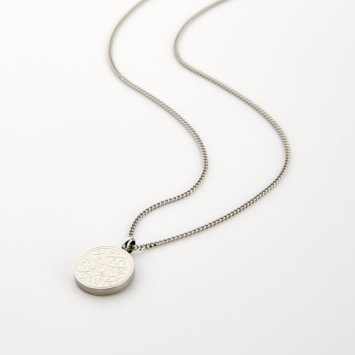 Silver necklace with a circular pendant engraved with 'Maktub' calligraphy, displayed on a white background.