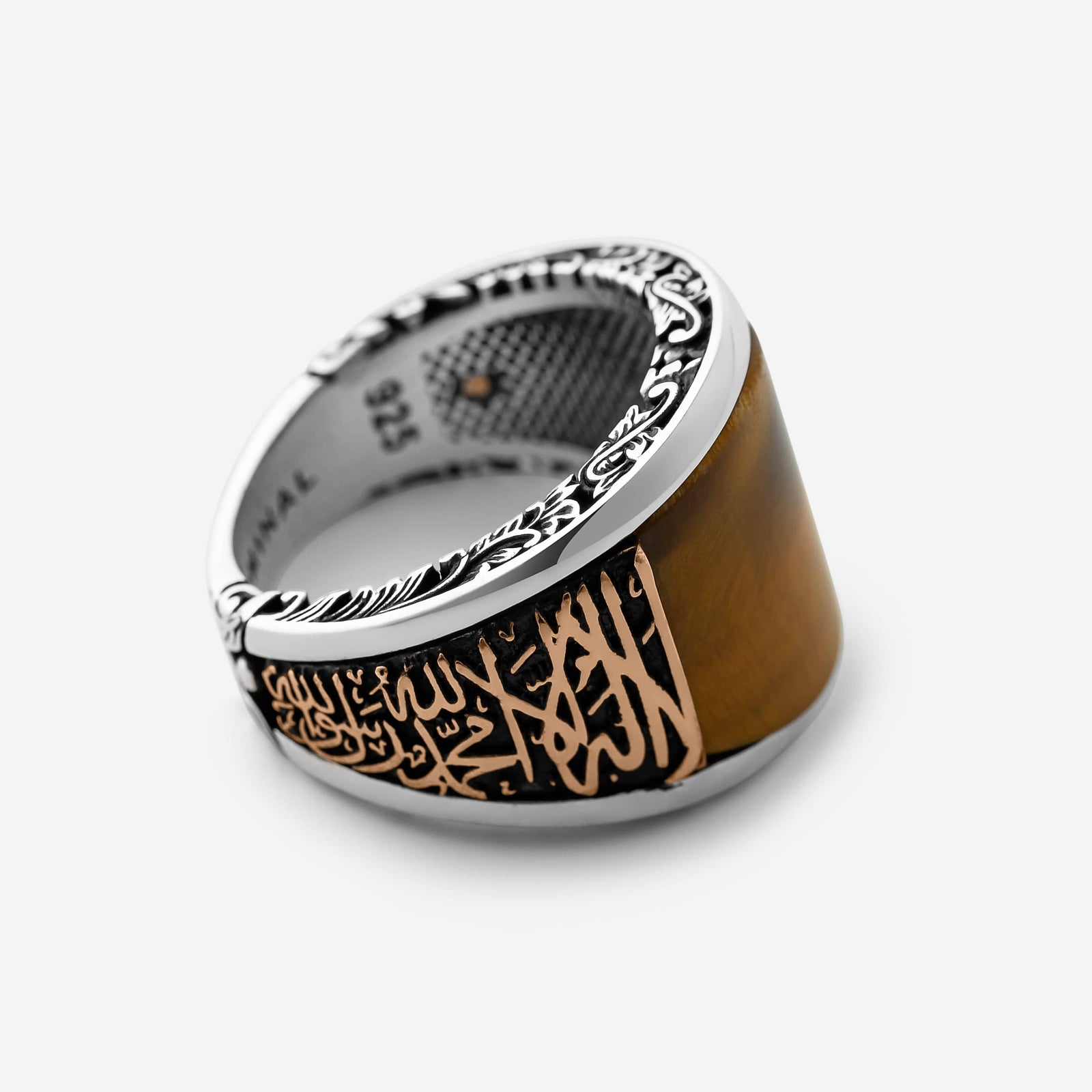 Photo of a men's ring that features smooth rounded Tiger's Eye stone, surrounded with bronze-toned calligraphy. Along the band, the Shahada, the declaration of faith, is embossed in elongated Arabic script, rising from the ring.