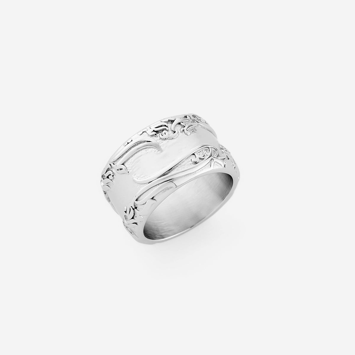A silver thick ring that features an iconic line from Rumi carved into a wide band: "The wound is where the light enters you." The center of the ring is smooth and traced floral details along the edges.