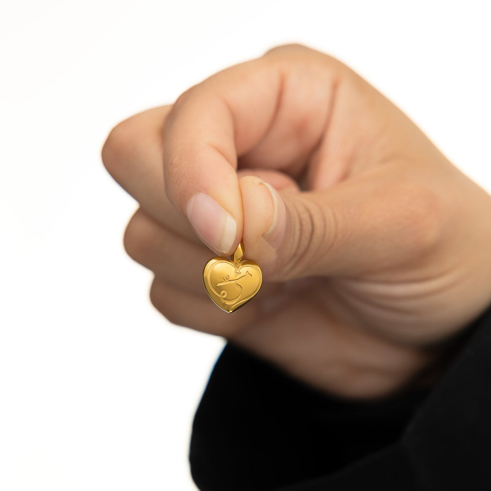 Photo of the model holding the gold Mama Heart Charm between their fingers.
