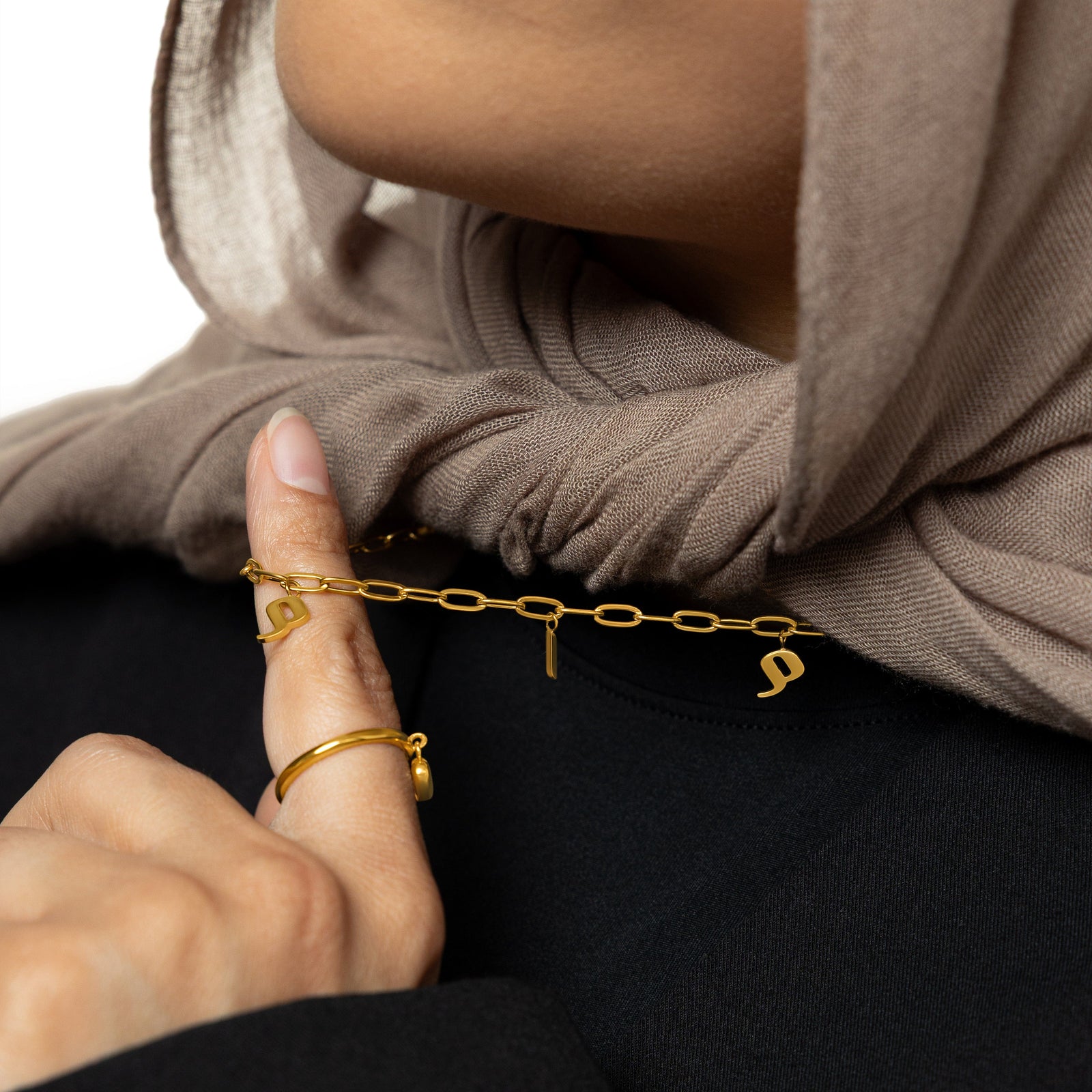 Close up of the gold Mama Charm Necklace as the model pulls the chain to show the pendants.