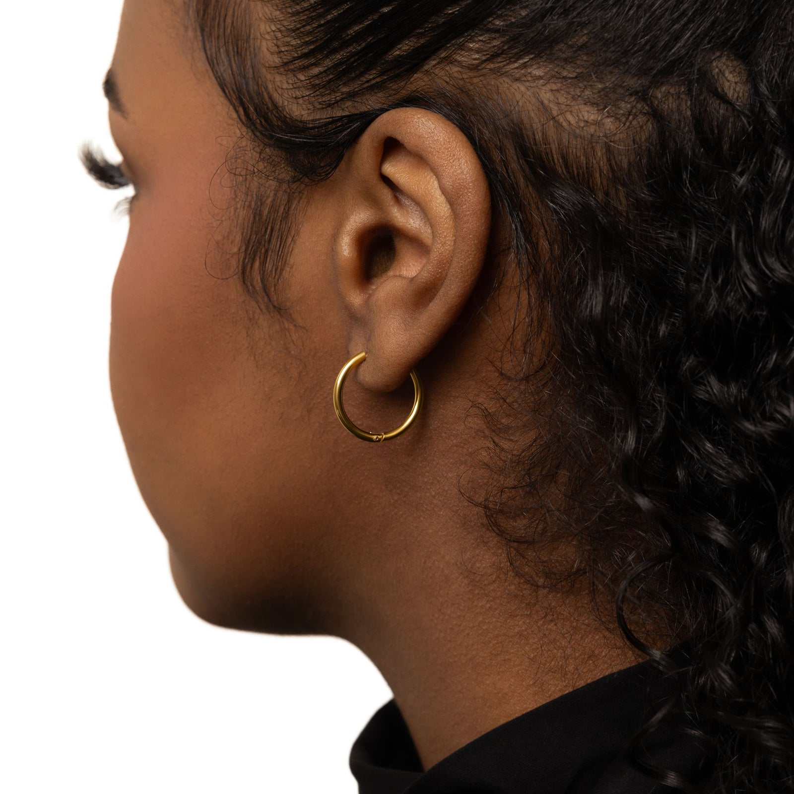 The gold Medium Essential Hoops | 16mm as worn by the model on their left ear.