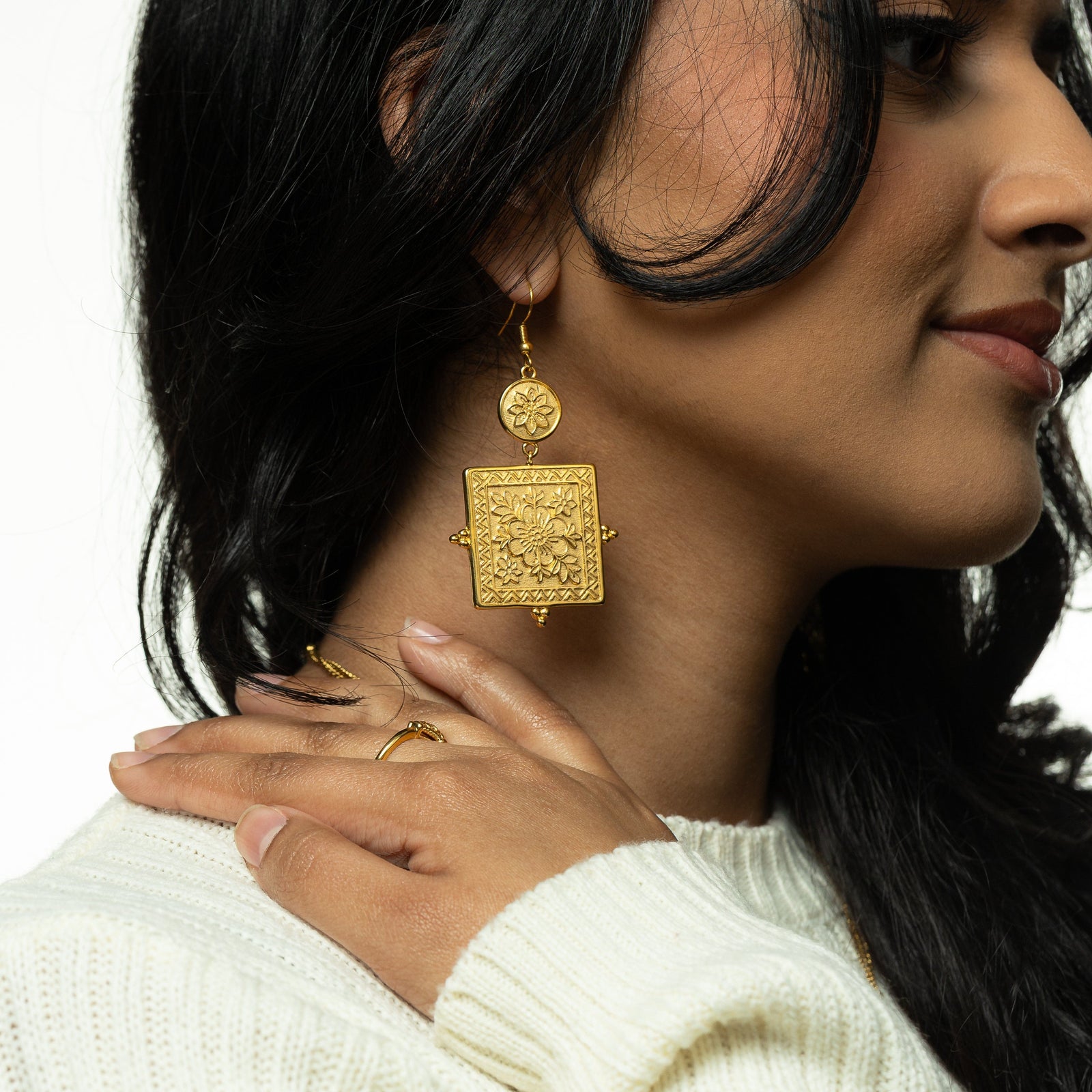 Woman wearing the gold Mehndi Floral Earrings and cream knit sweater, showing the statement floral pendant design.