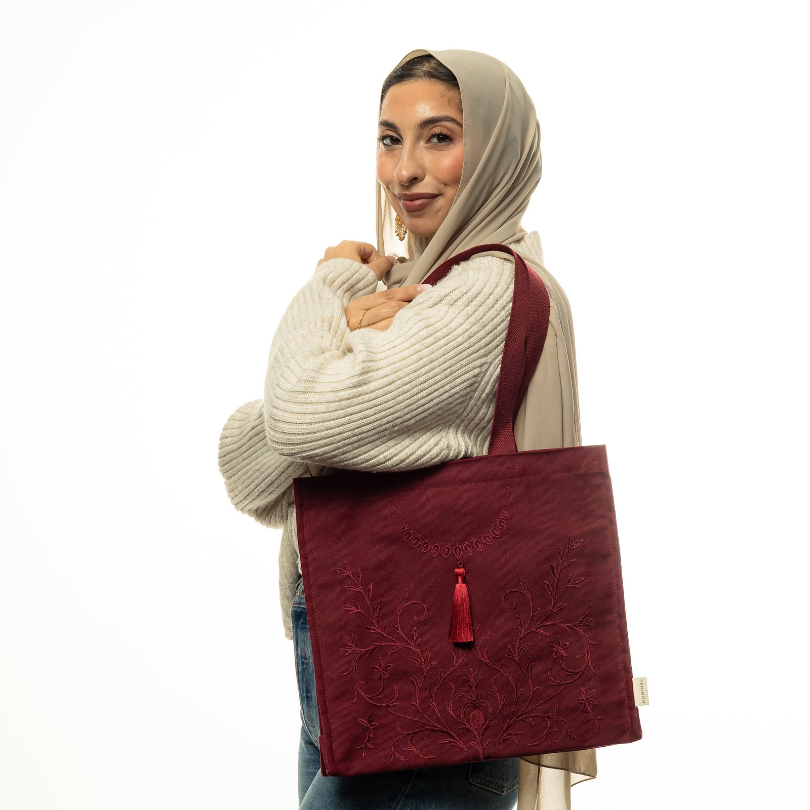 Photo of model smiling to the camera while carrying the maroon Mehndi Floral Tote on their left shoulder.