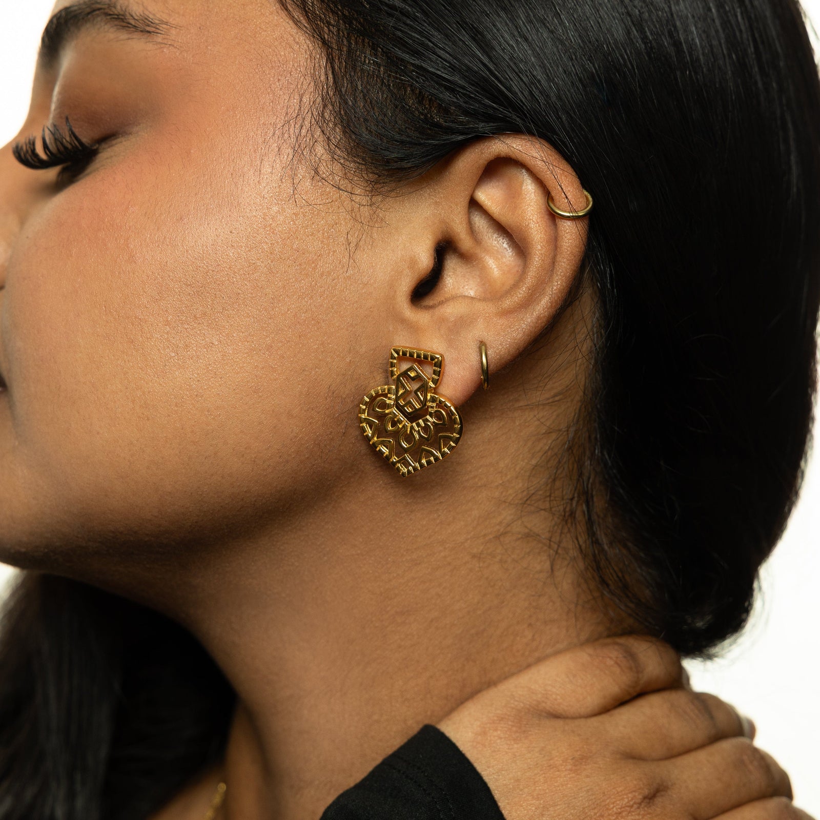 Side profile of woman wearing the gold Mehndi Heart Earring, styled with a black top and gold necklace.