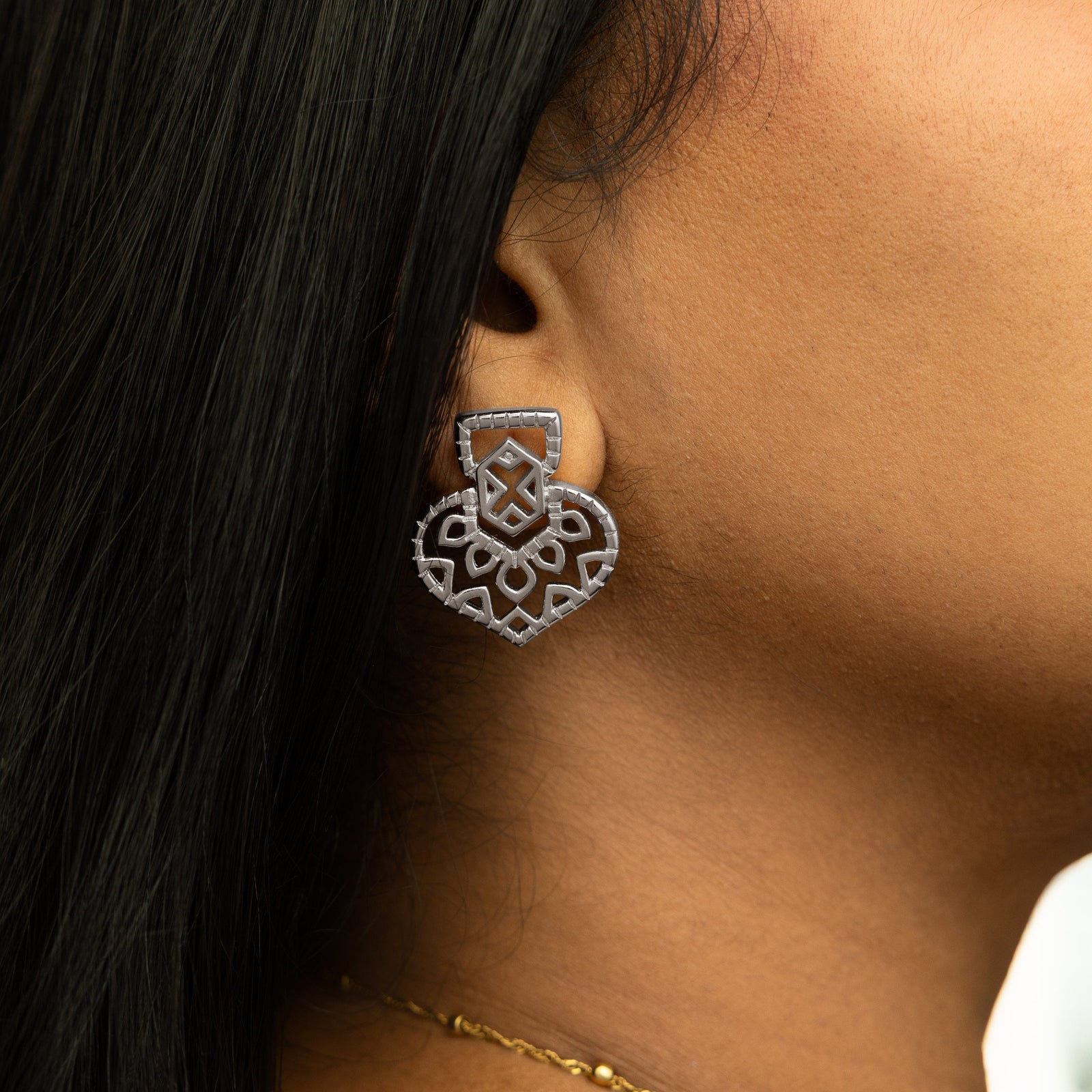 Close-up of one silver Mehndi Heart Earring worn on ear, showing its intricate heart-shaped cutout pattern.
