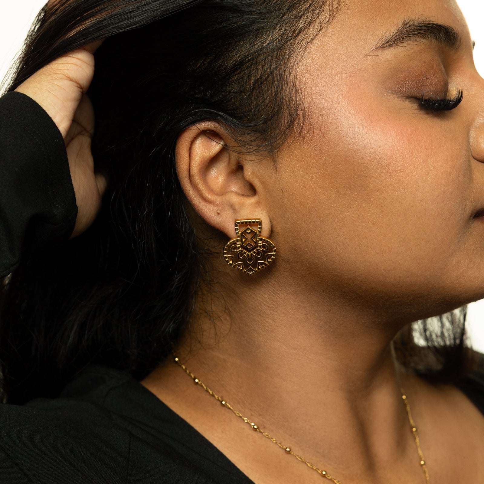 Side profile of woman wearing the gold Mehndi Heart Earring, styled with a black top and gold necklace.