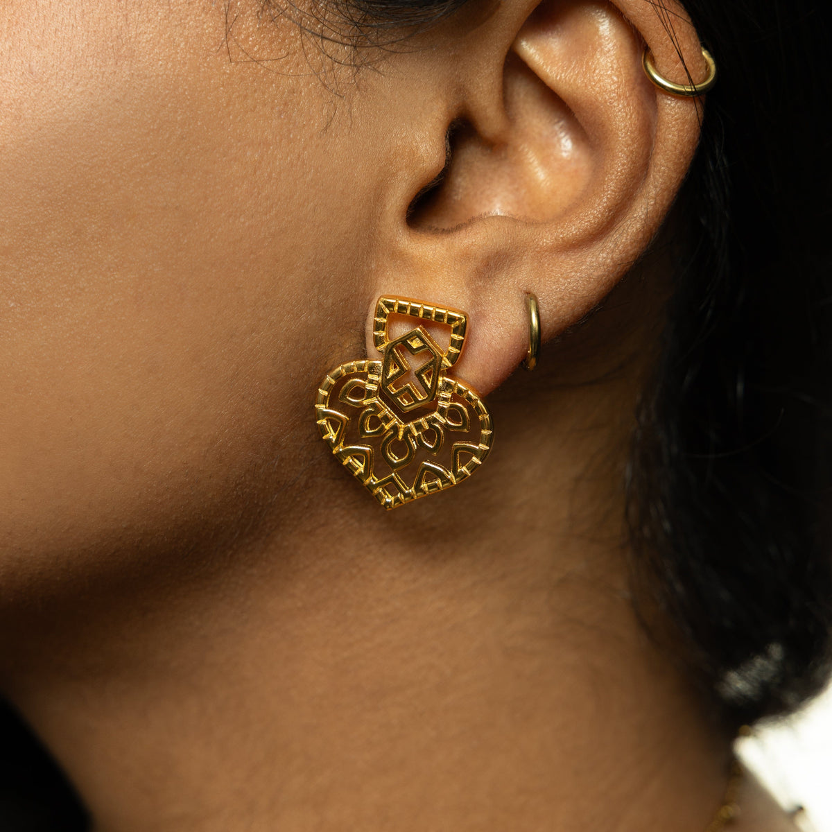 Close-up of one gold Mehndi Heart Earring worn on ear, showing its intricate heart-shaped cutout pattern.