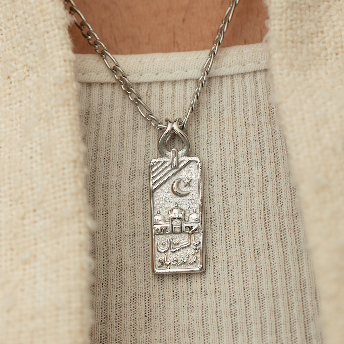 Silver Pakistan Zindabad Necklace worn over a cream knit top, showing the engraved pendant details.