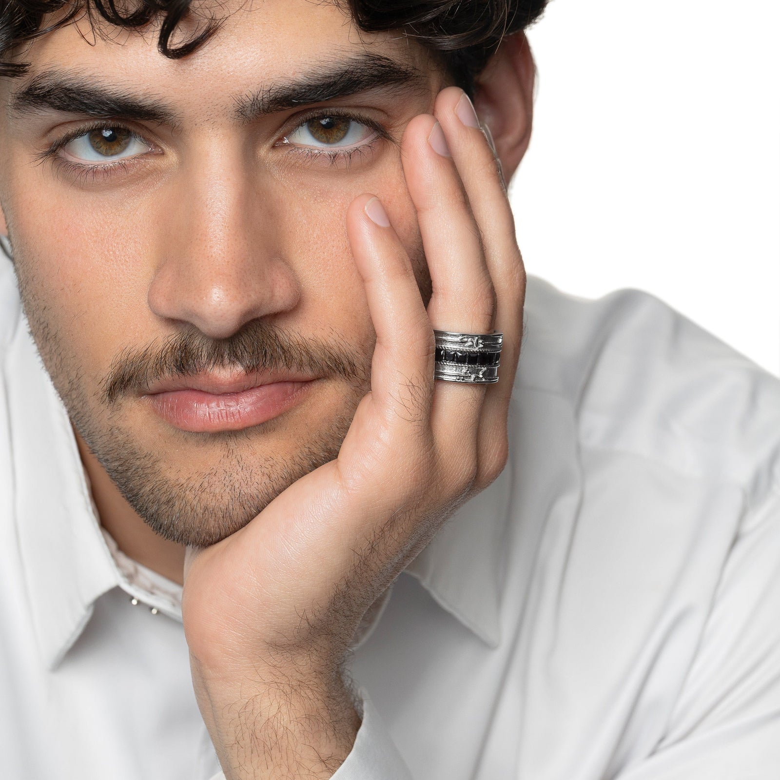 Photo of the model resting their head on their left hand. The model is wearing the silver "Perhaps you dislike what's good for you" Stripe Ring | Men on their left ring finger.