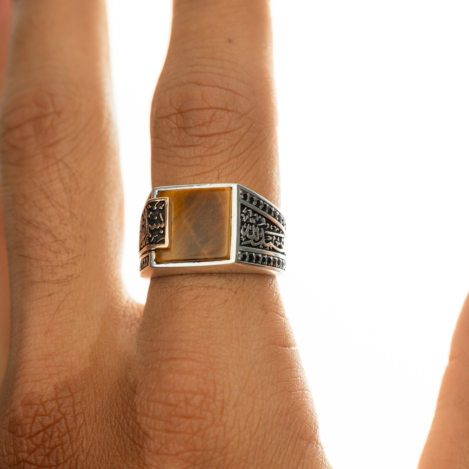 Silver men’s ring with a tiger's eye stone and Arabic calligraphy reading ‘Bismillah, Alhamdulillah,’ shown on a man’s hand