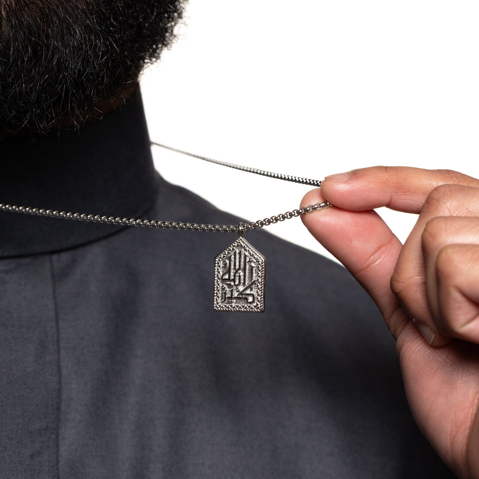 Model holds the chain to show the pendant of the silver "Allahu Akbar" Calligraphy Necklace