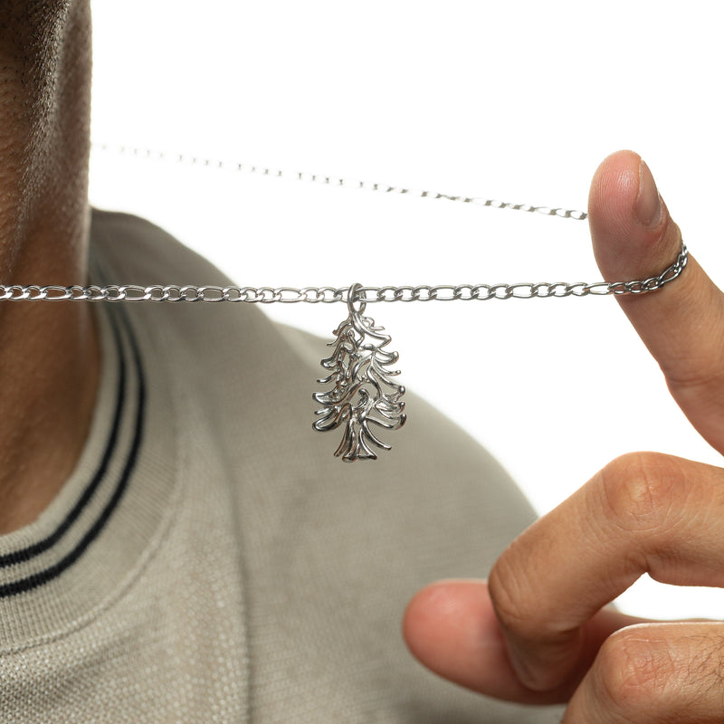 Close-up of the ‘Freedom is the Soul’ Lebanon Cedar Necklace | Men as the man lifts the chain to show the silver cedar pendant.