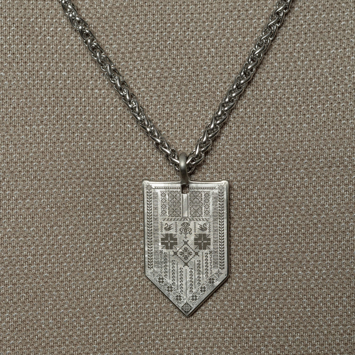 Man wearing the Hanging Tatreez Necklace | Men, featuring a silver Tatreez-engraved pendant on a thick chain.
