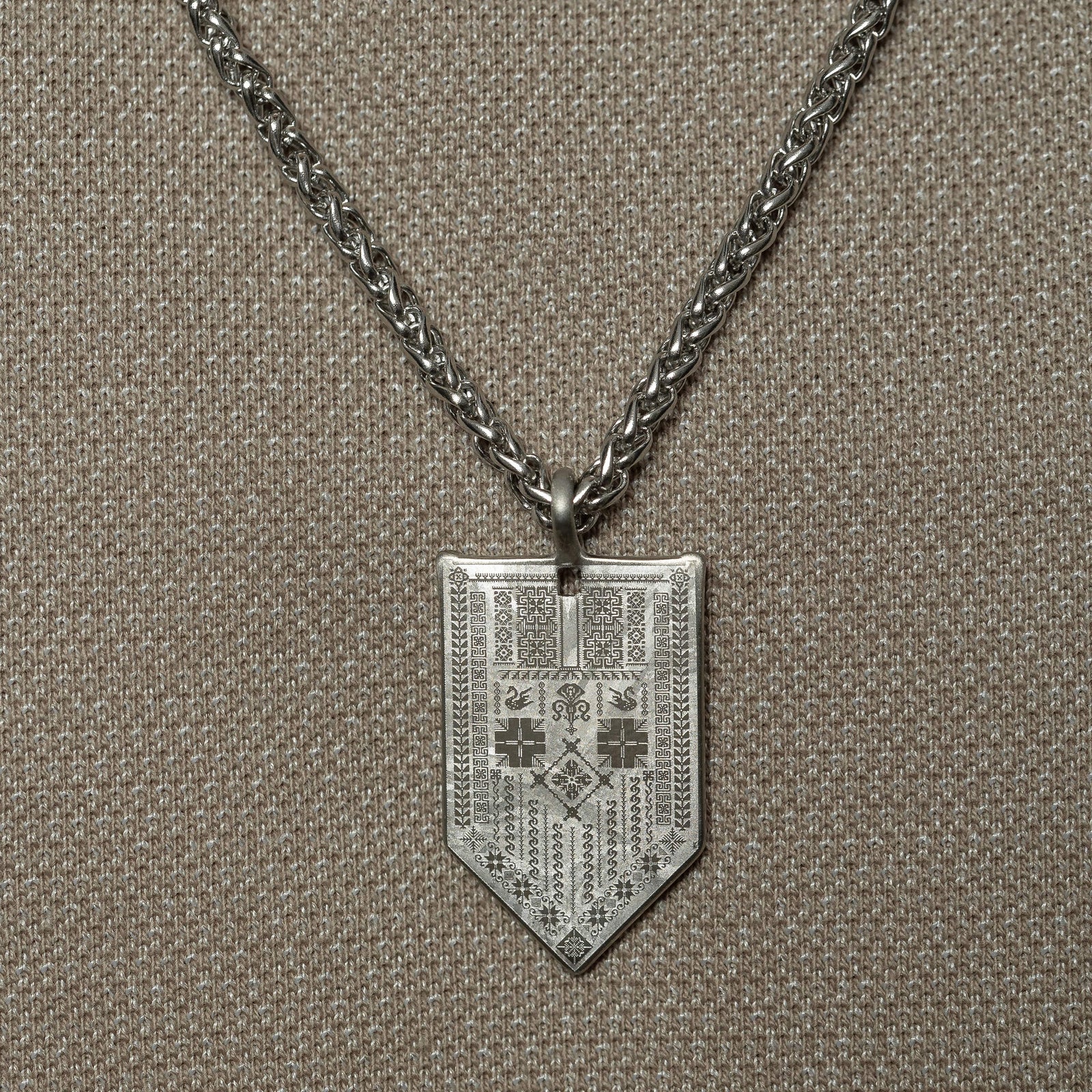 Man wearing the Hanging Tatreez Necklace | Men, featuring a silver Tatreez-engraved pendant on a thick chain.