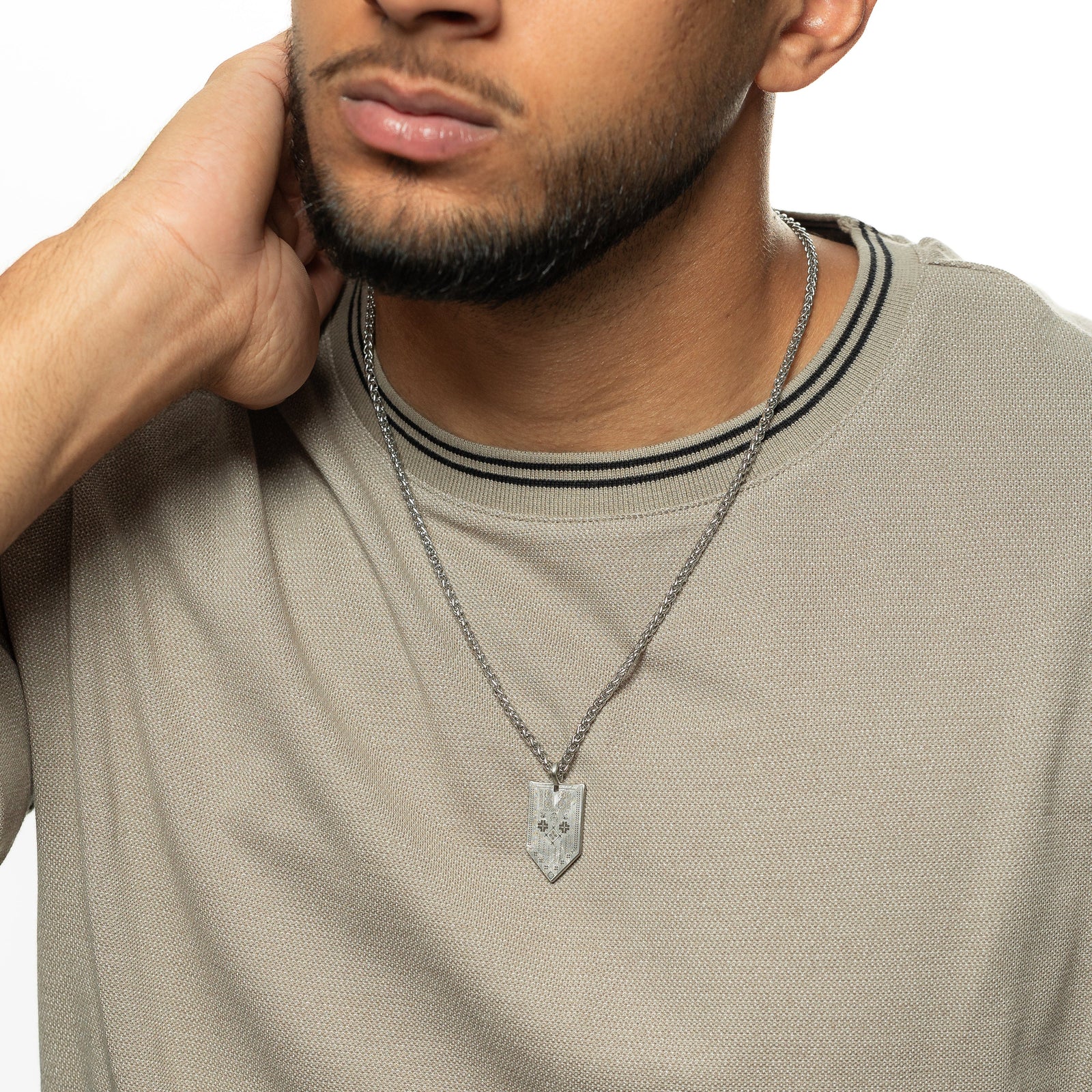 Man wearing the Hanging Tatreez Necklace | Men with a silver patterned pendant.”