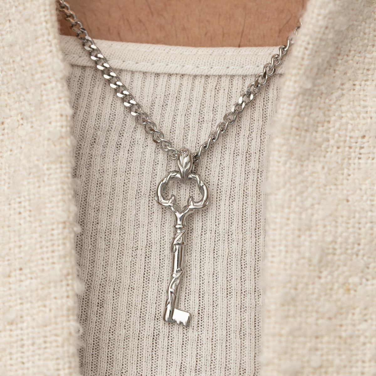 Man wearing the stainless steel Palestine Key of Return Necklace, styled over a textured cream shirt.