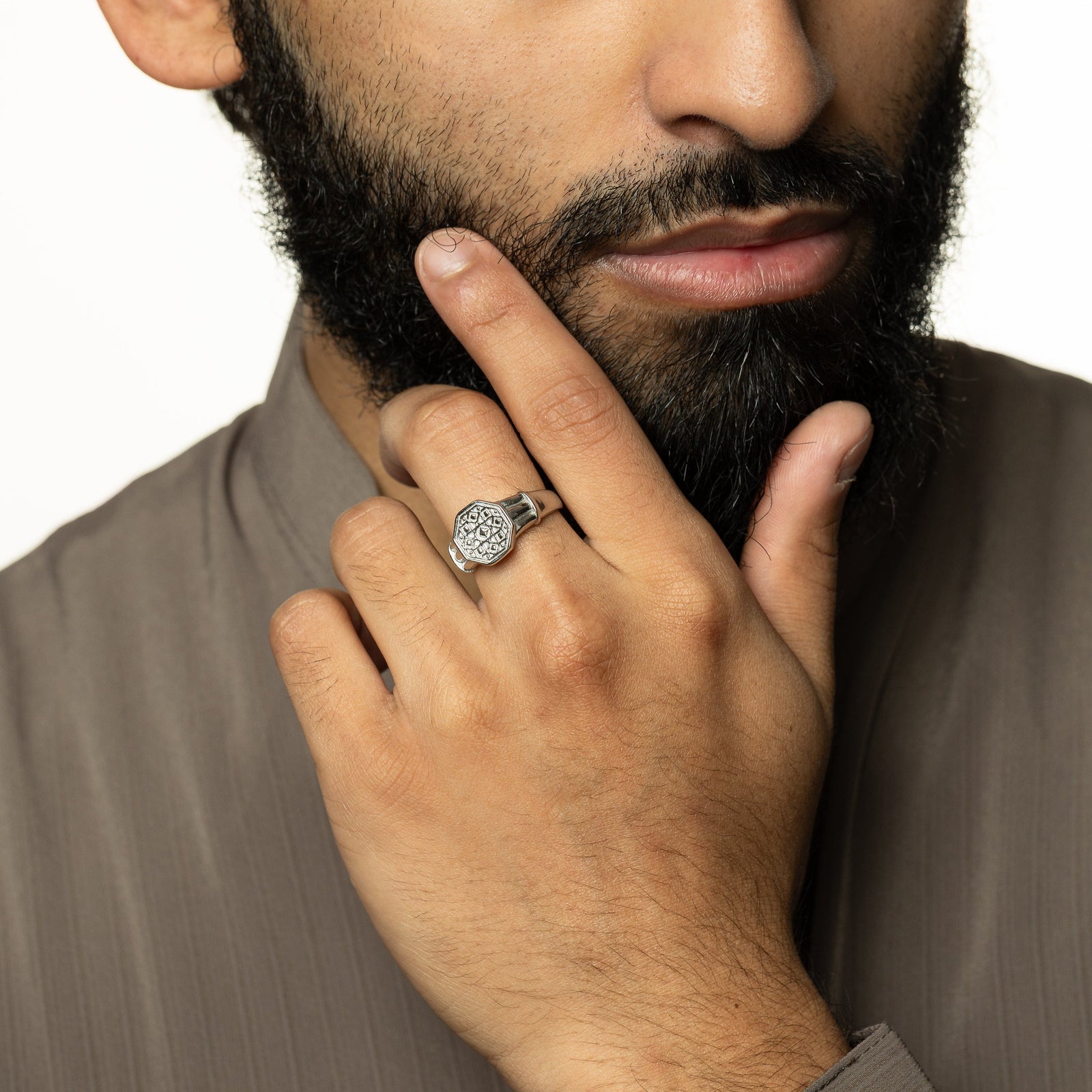 Model holds their face showing the silver ring worn on their left middle finger.