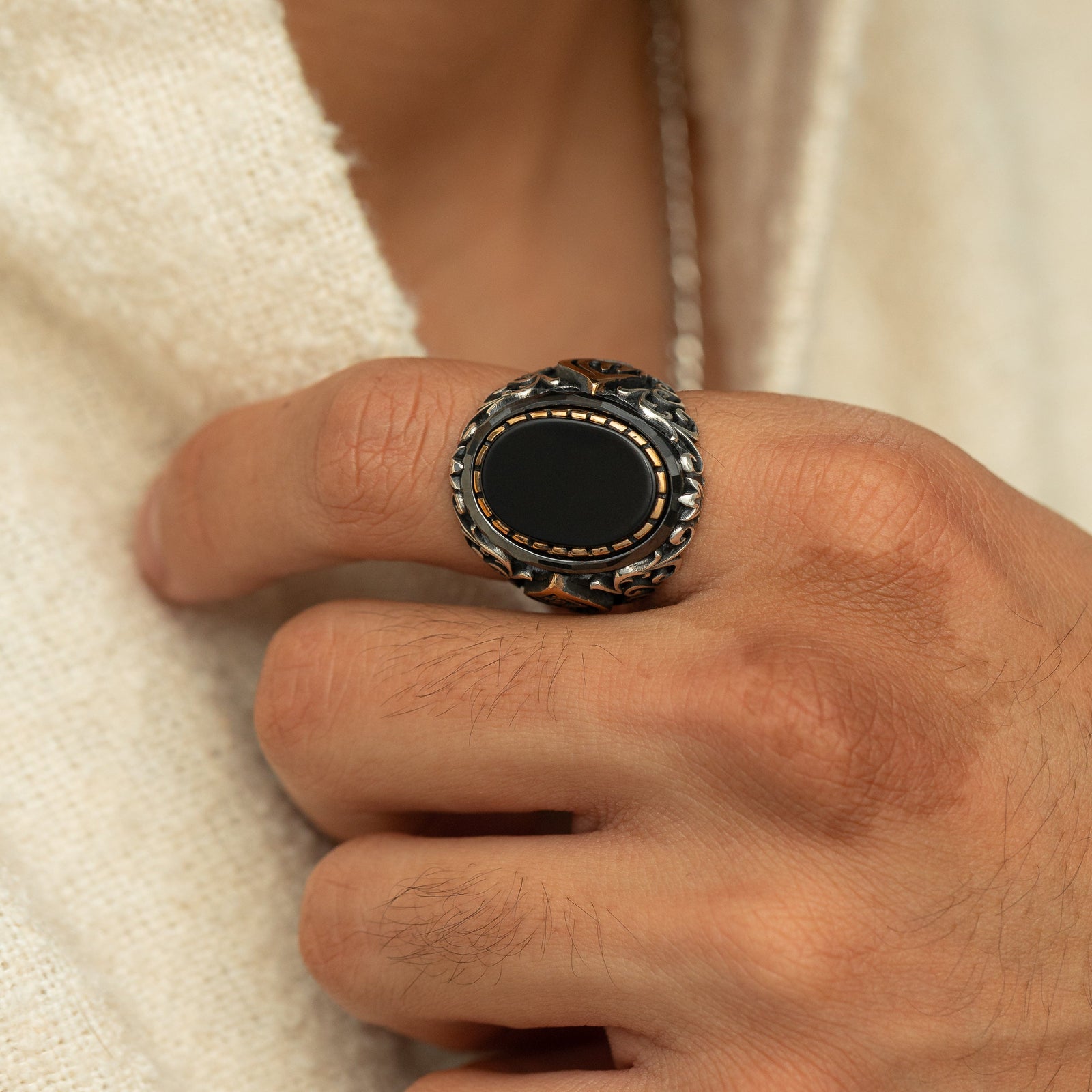 Man wearing silver ring with a black onyx stone and an Arabic calligraphy detail of the word ‘Allah,’ surrounded by ornate black and silver engravings.