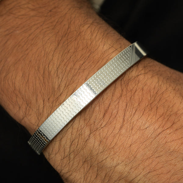 silver Keffiyeh Bracelet worn on the wrist, showing the engraved keffiyeh pattern across the band.