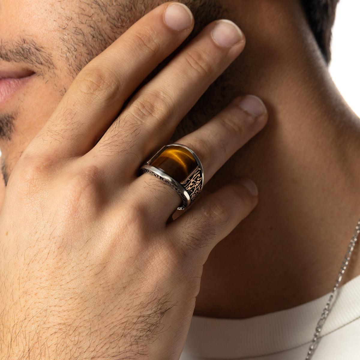 Close up of the model's right hand showing the Shahada Tiger's Eye Sterling Silver Ring they are wearing on their ring finger.