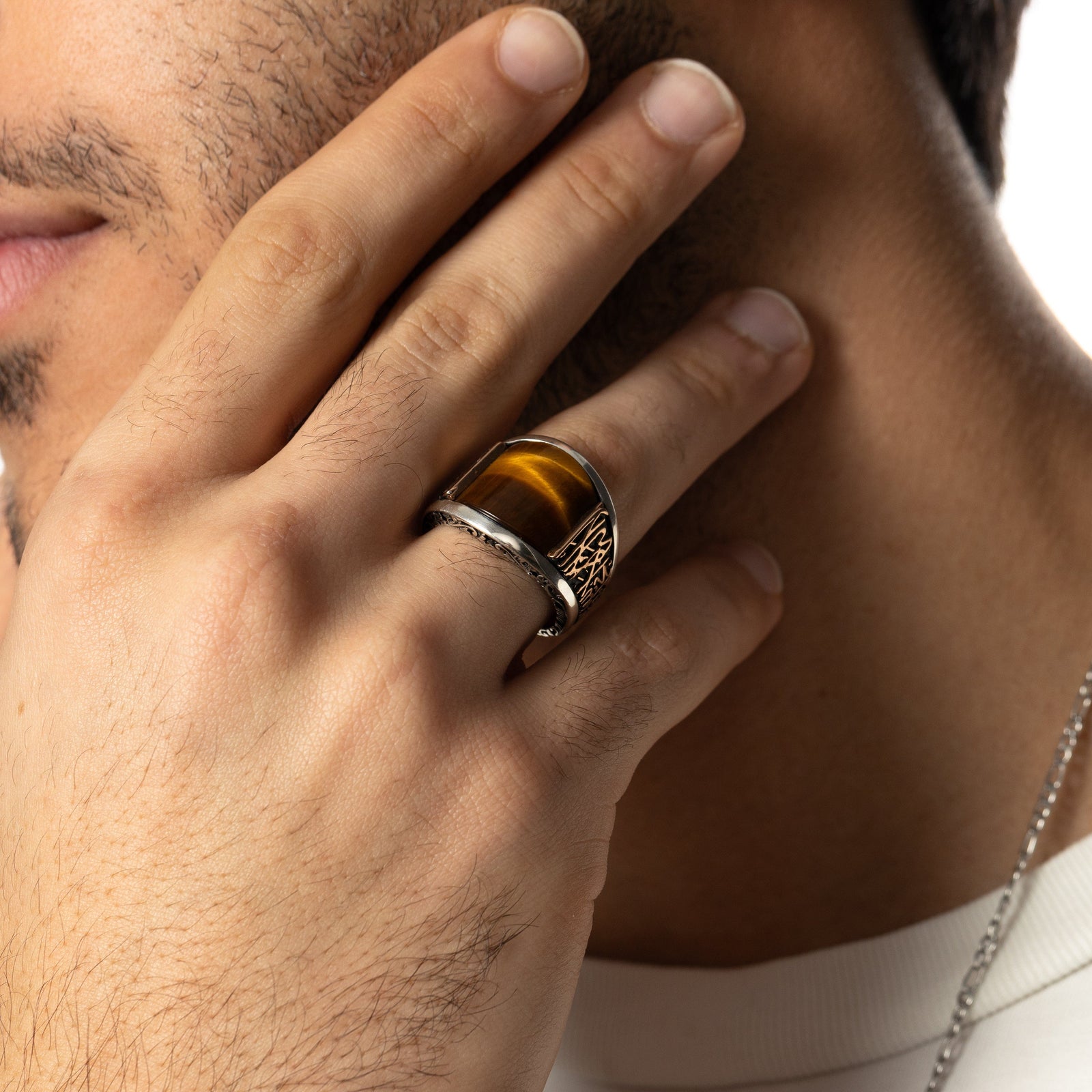 Close up of the model's right hand showing the Shahada Tiger's Eye Sterling Silver Ring they are wearing on their ring finger.