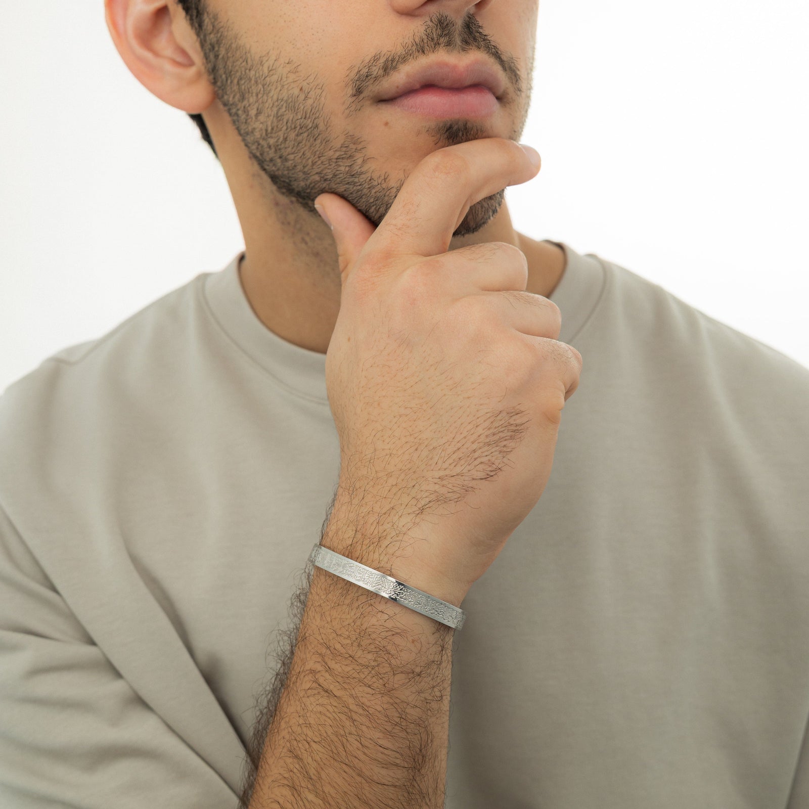 Photo of the silver Ayatul Kursi Cuff | Men as worn by the model on their right hand.