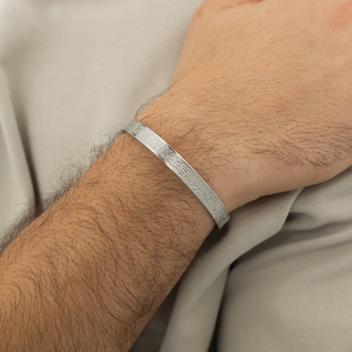 Close up of the silver Ayatul Kursi Cuff | Men as worn by the model on their right wrist.