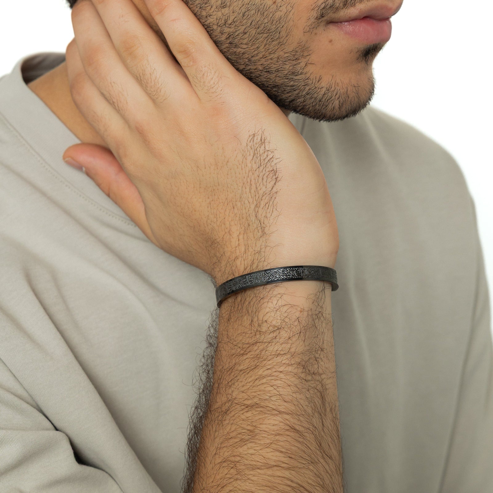 The black Ayatul Kursi Cuff | Men - as worn by the model on their right wrist.