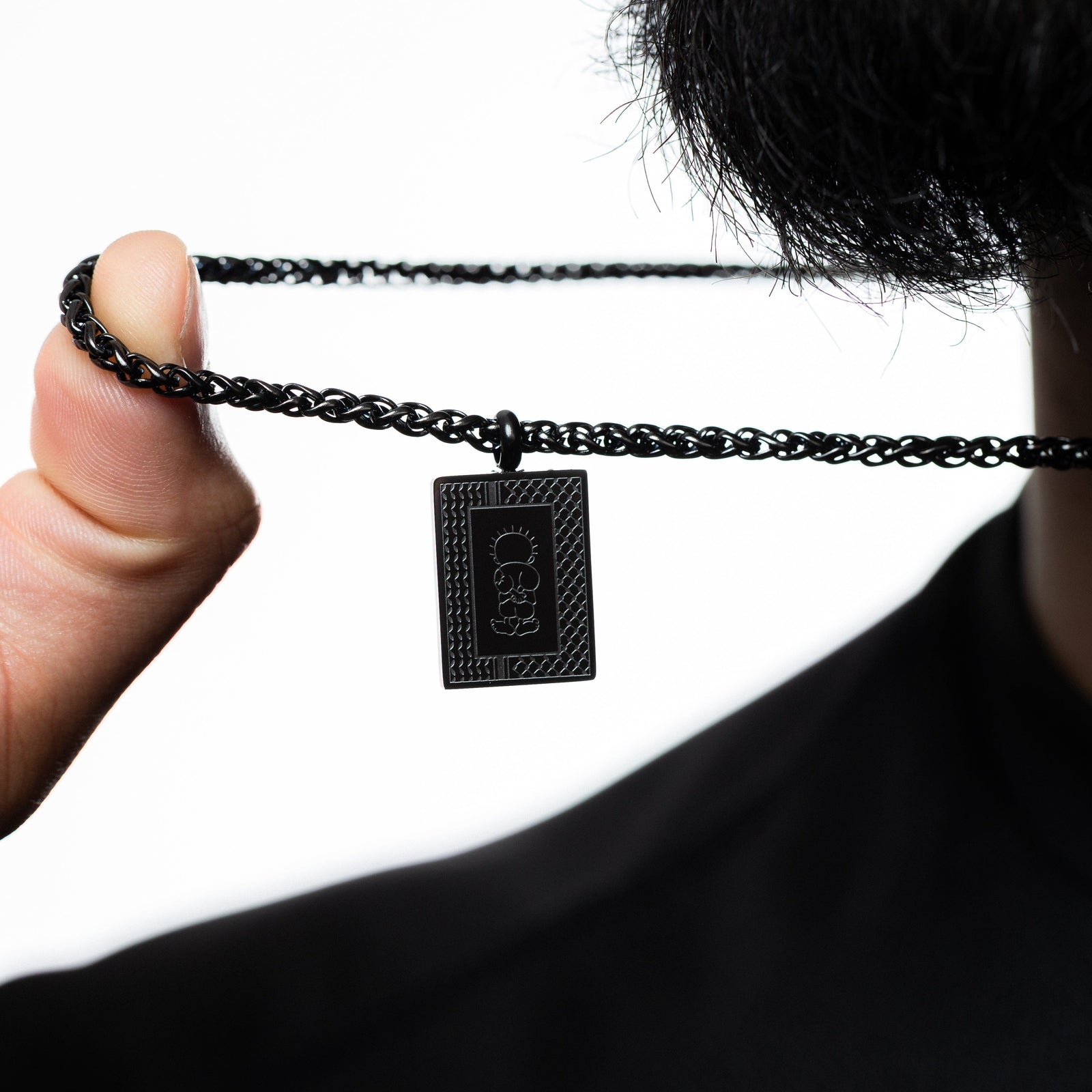 Black Handala Necklace held by a hand against a white background