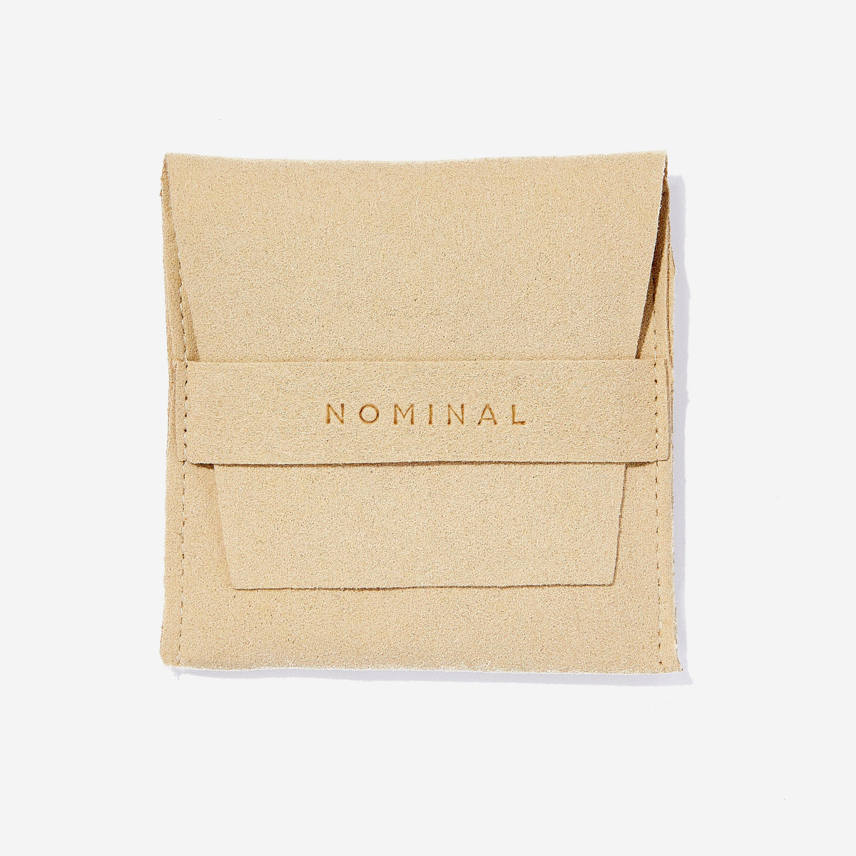 Beige suede jewelry pouch with stitched edges and fold-over flap, featuring the word ‘NOMINAL’ debossed across the front strap.