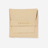 Beige suede jewelry pouch with 'NOMINAL' pressed in lettering on the front flap strap, flat against a light background.