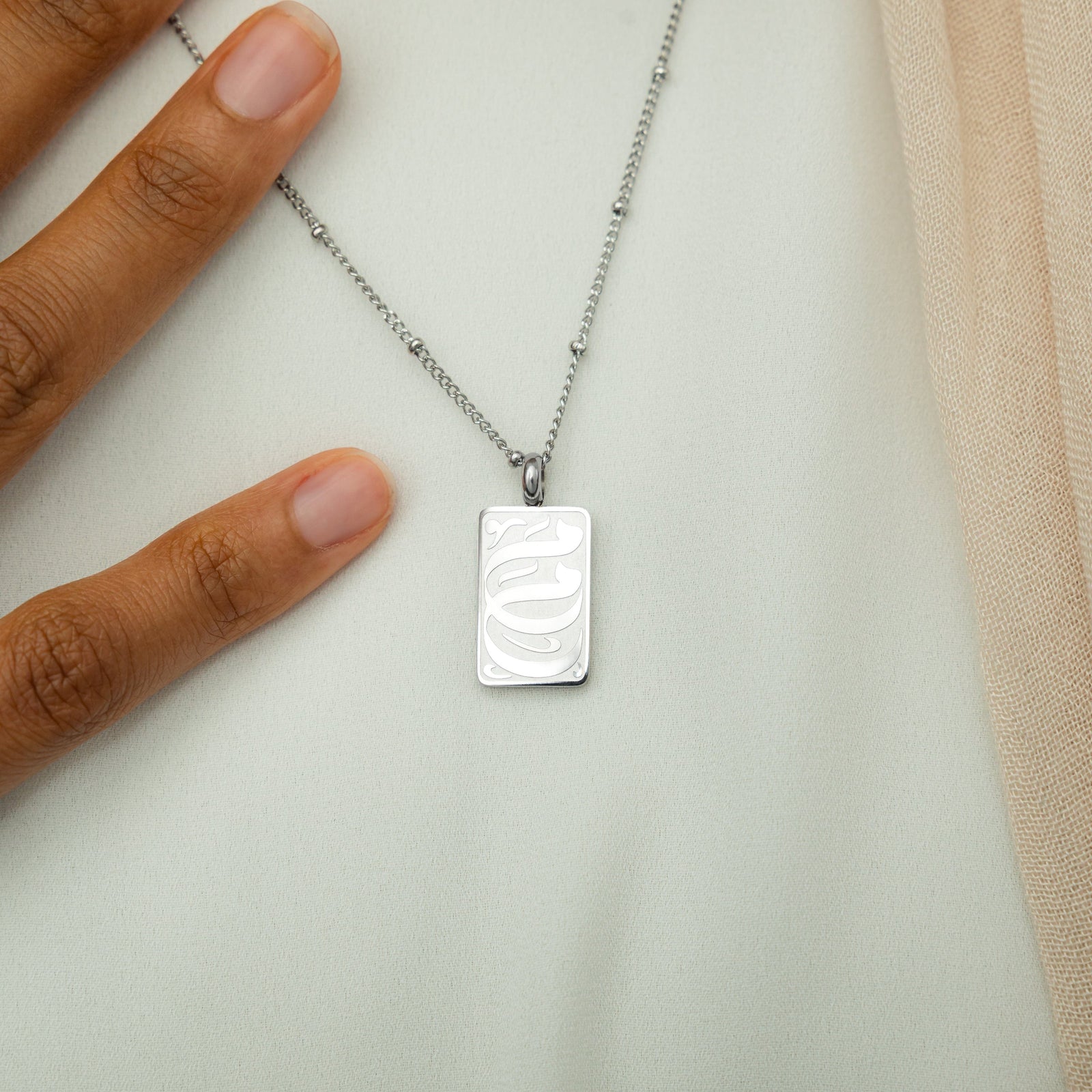 Close up of the My Mother Tag Necklace resting against the white fabric of the model's shirt.