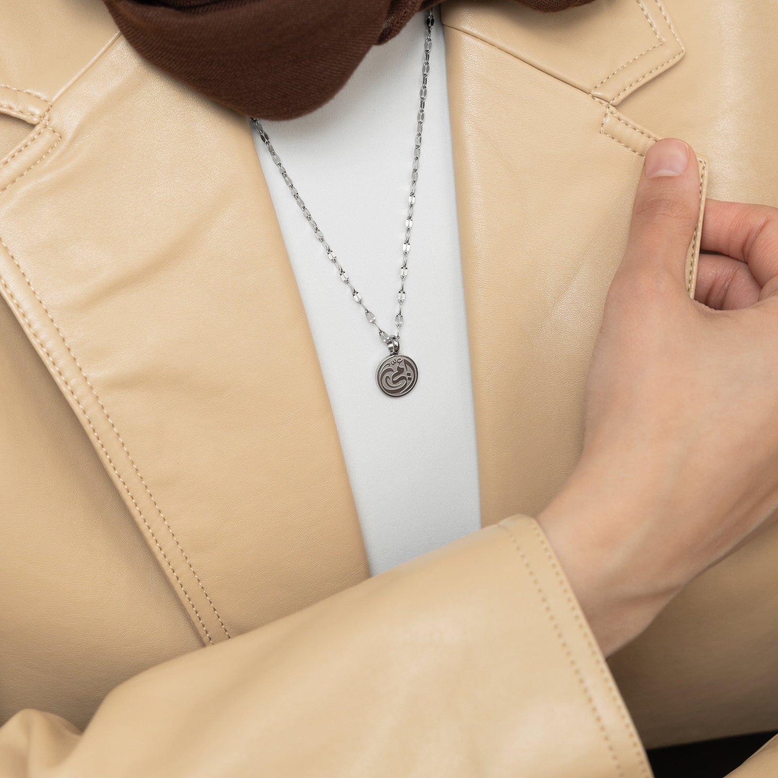 A model showcasing the silver My Mother Necklace. The pendant sits delicately on her collarbone, emphasizing the smooth Arabic script against a minimalist ensemble.