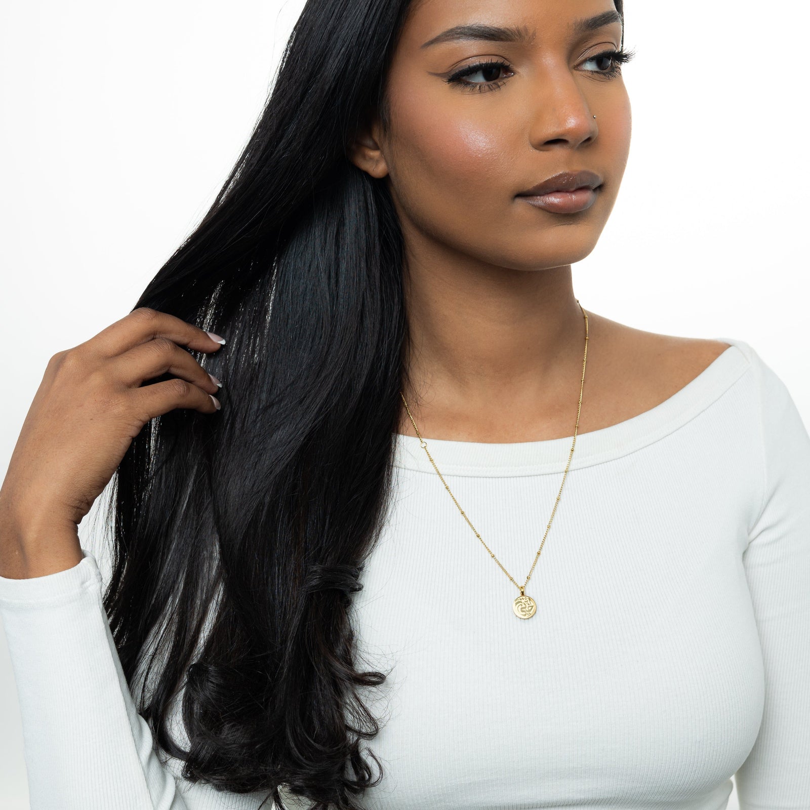 Photo of the model moving their hair away to show the necklace they are wearing.