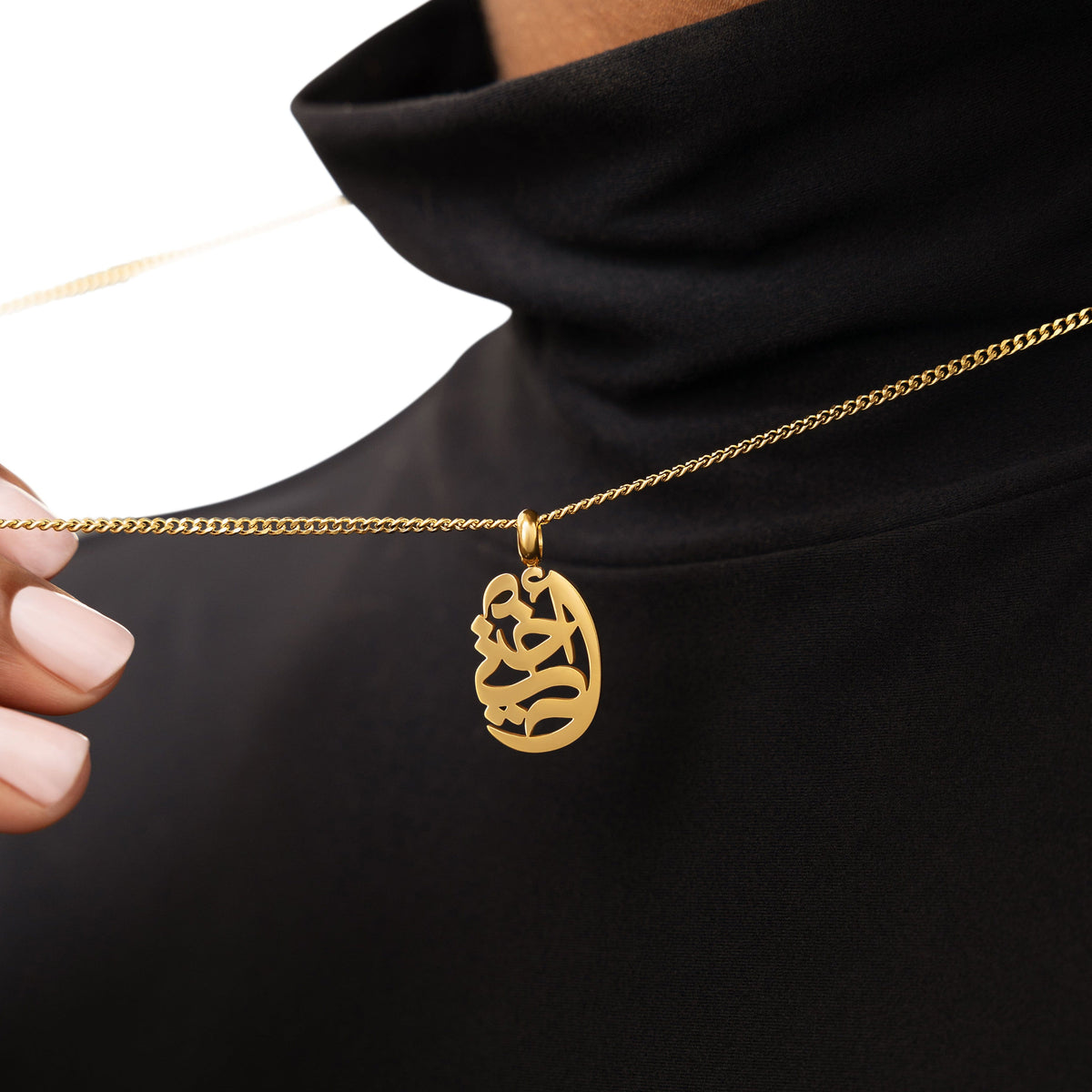 A model wearing the 18K gold-plated My Sister Oval Necklace. The pendant rests gracefully on her collarbone, highlighting the intricate Arabic calligraphy against a neutral-toned outfit.