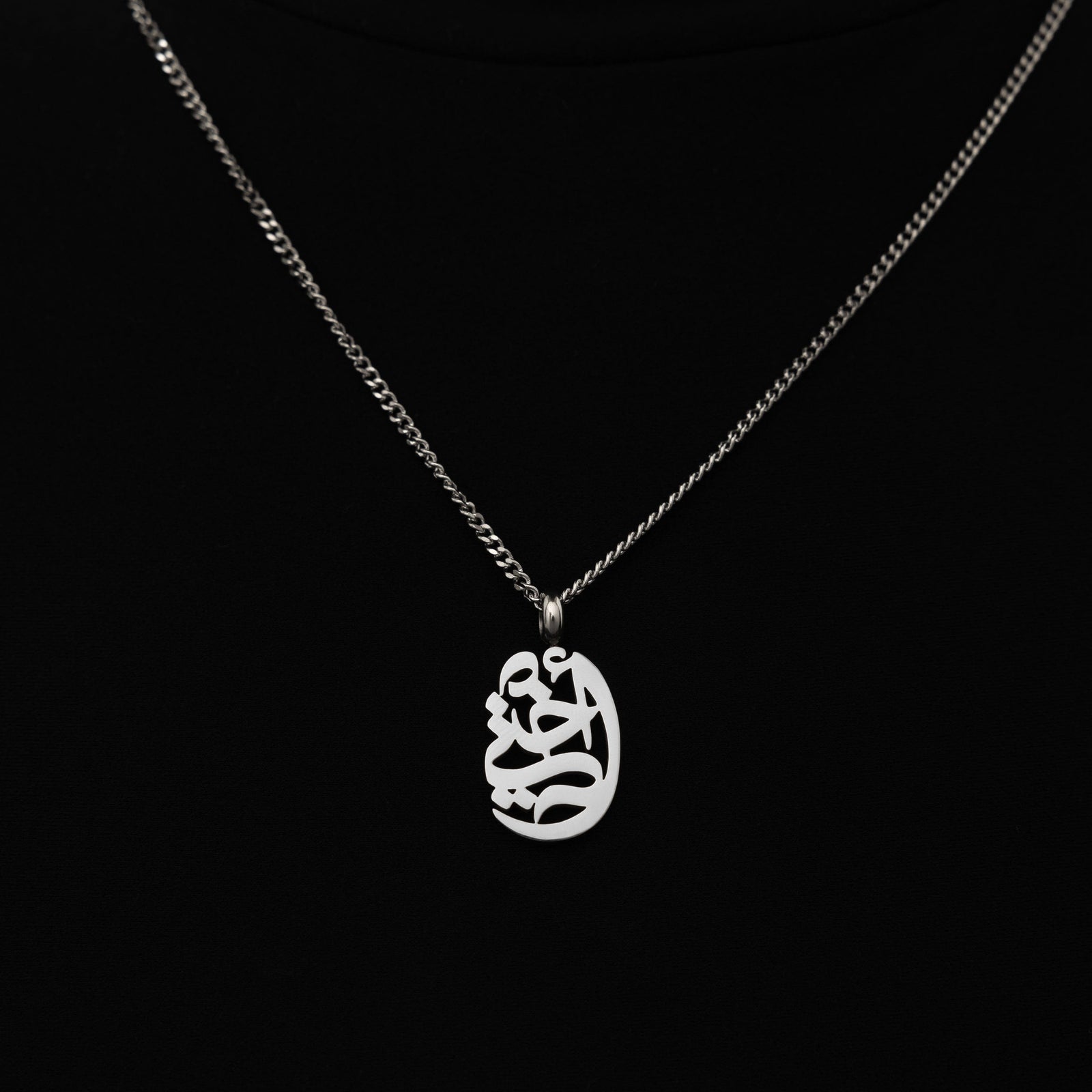 The My Sister Oval Necklace in a polished silver finish, showcasing the oval pendant engraved with "أختي" ("Ukhti" – My Sister) in graceful Arabic script, hanging from a sleek silver curb chain.
