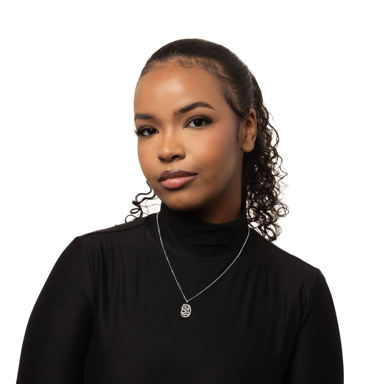 A model showcasing the silver My Sister Oval Necklace. The pendant sits delicately on her collarbone, emphasizing the smooth Arabic script against a minimalist ensemble.