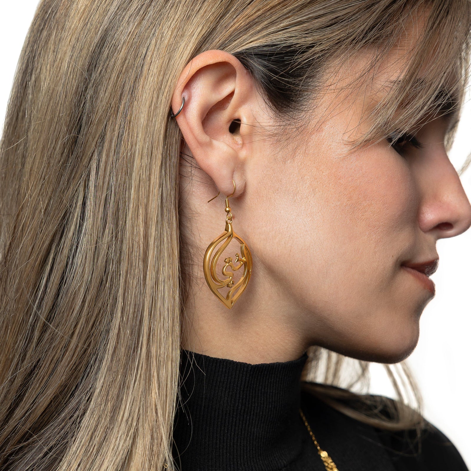 Photo of the right side of the model's face showing the gold "My Sister" Droplet Earrings they are wearing.