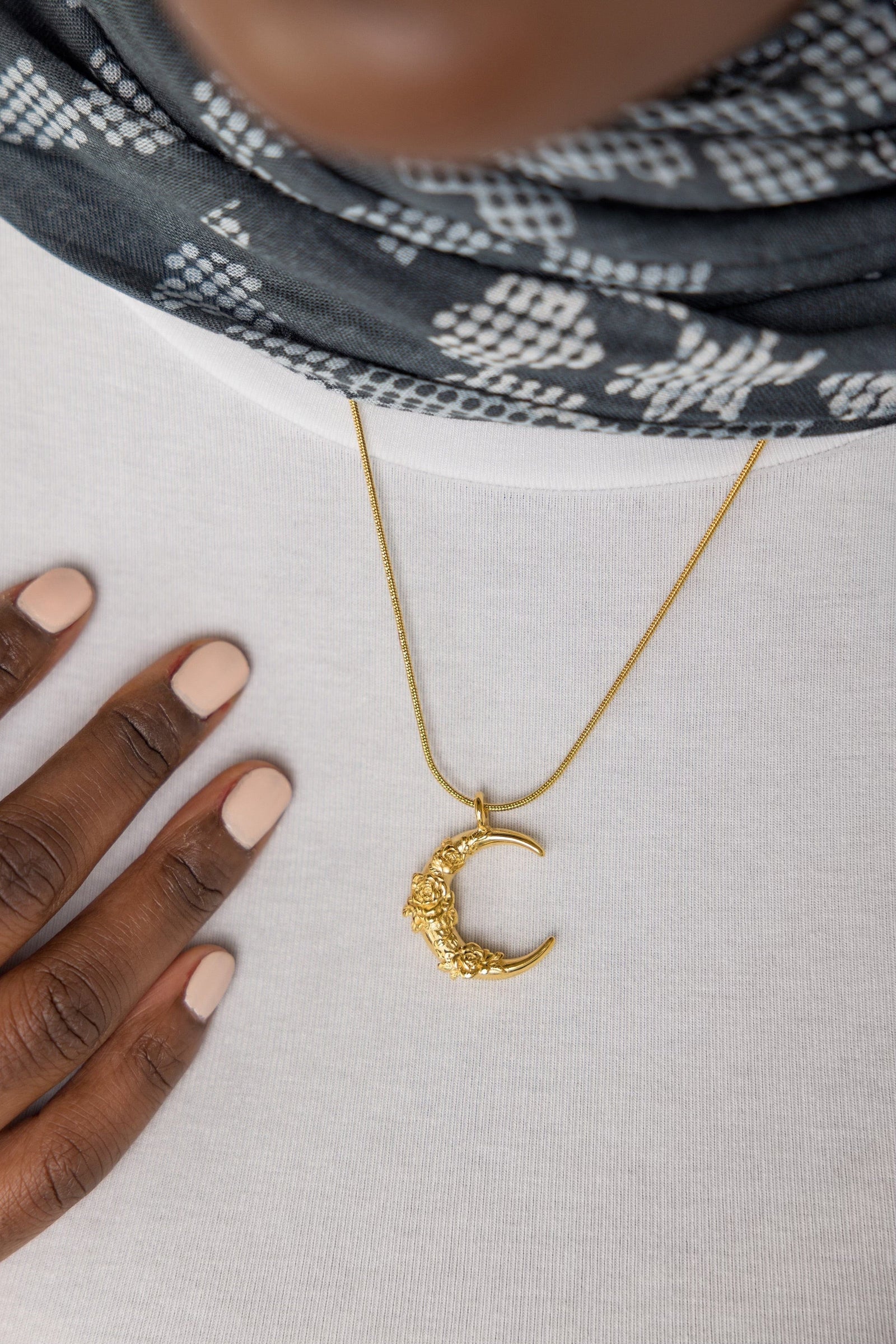 A model wearing the Damask Rose Crescent Necklace at its full 22-inch length. The necklace rests gracefully on the collarbone, highlighting the crescent moon pendant with rose detailing against a simple, neutral-toned outfit.