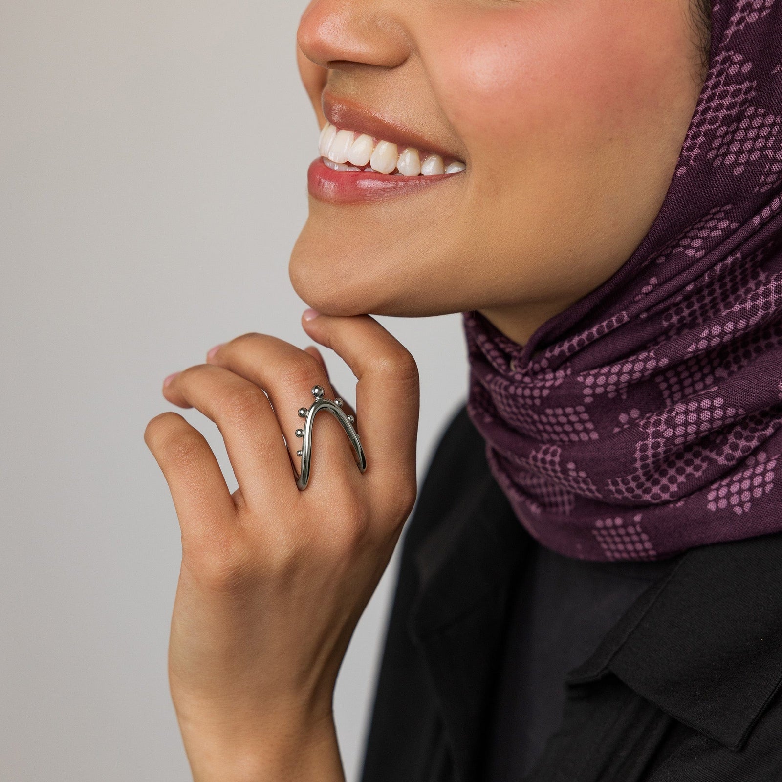Woman wearing a purple patterned hijab and black outfit, showing the silver Orbiting Ring on her finger.