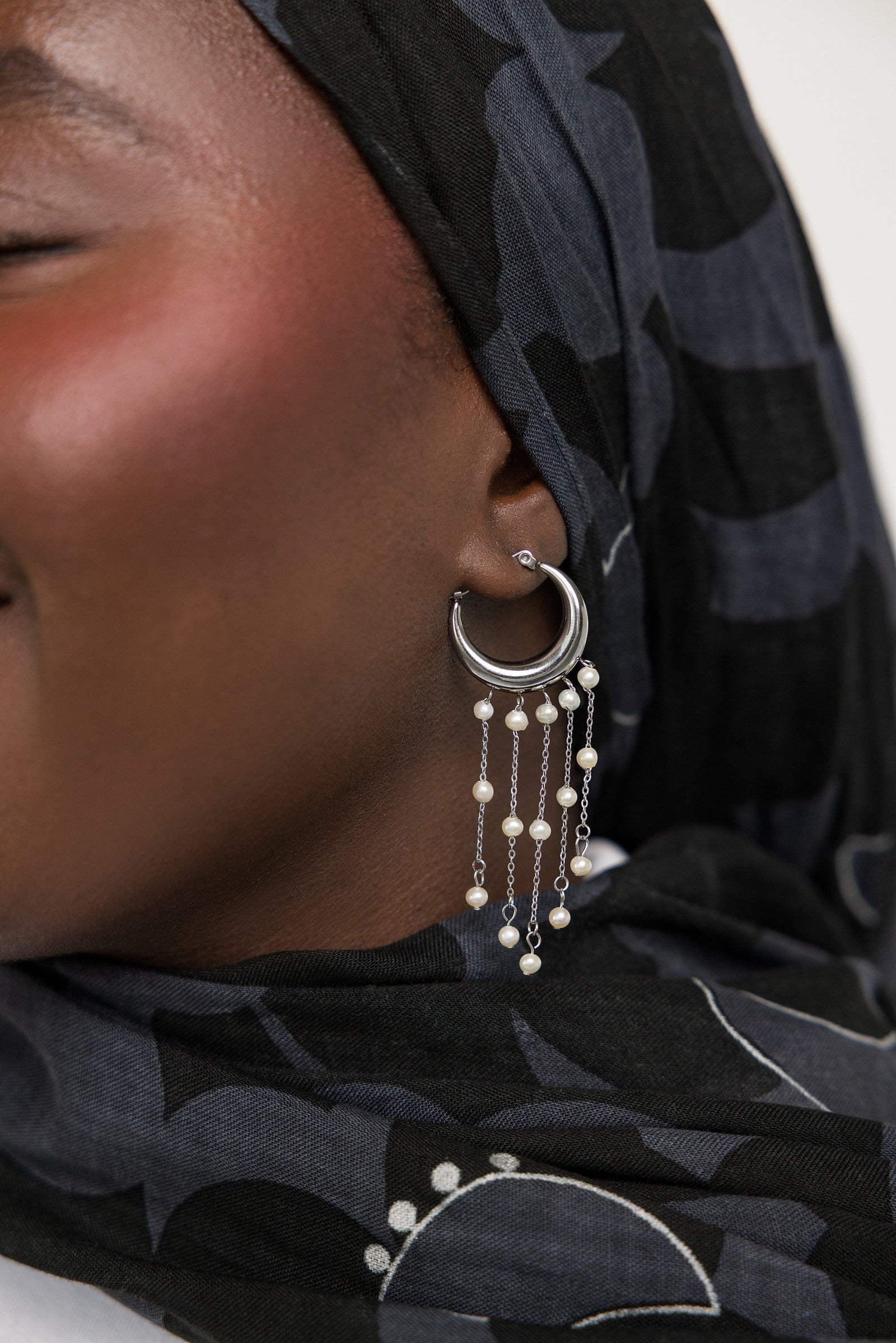 Close up of the silver Raining Pearl Hoop earring as worn by the model on their left ear. 