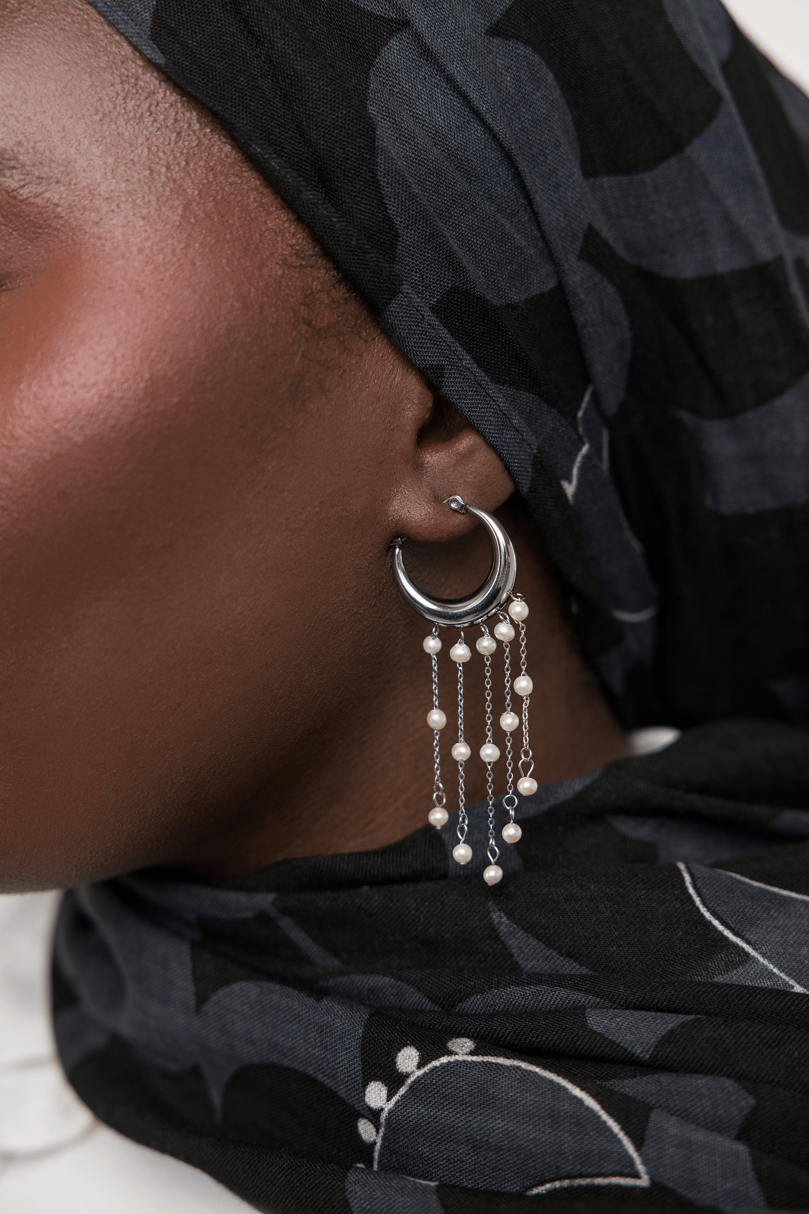 Close up of the silver Raining Pearl Hoop earring as worn by the model on their left ear. 