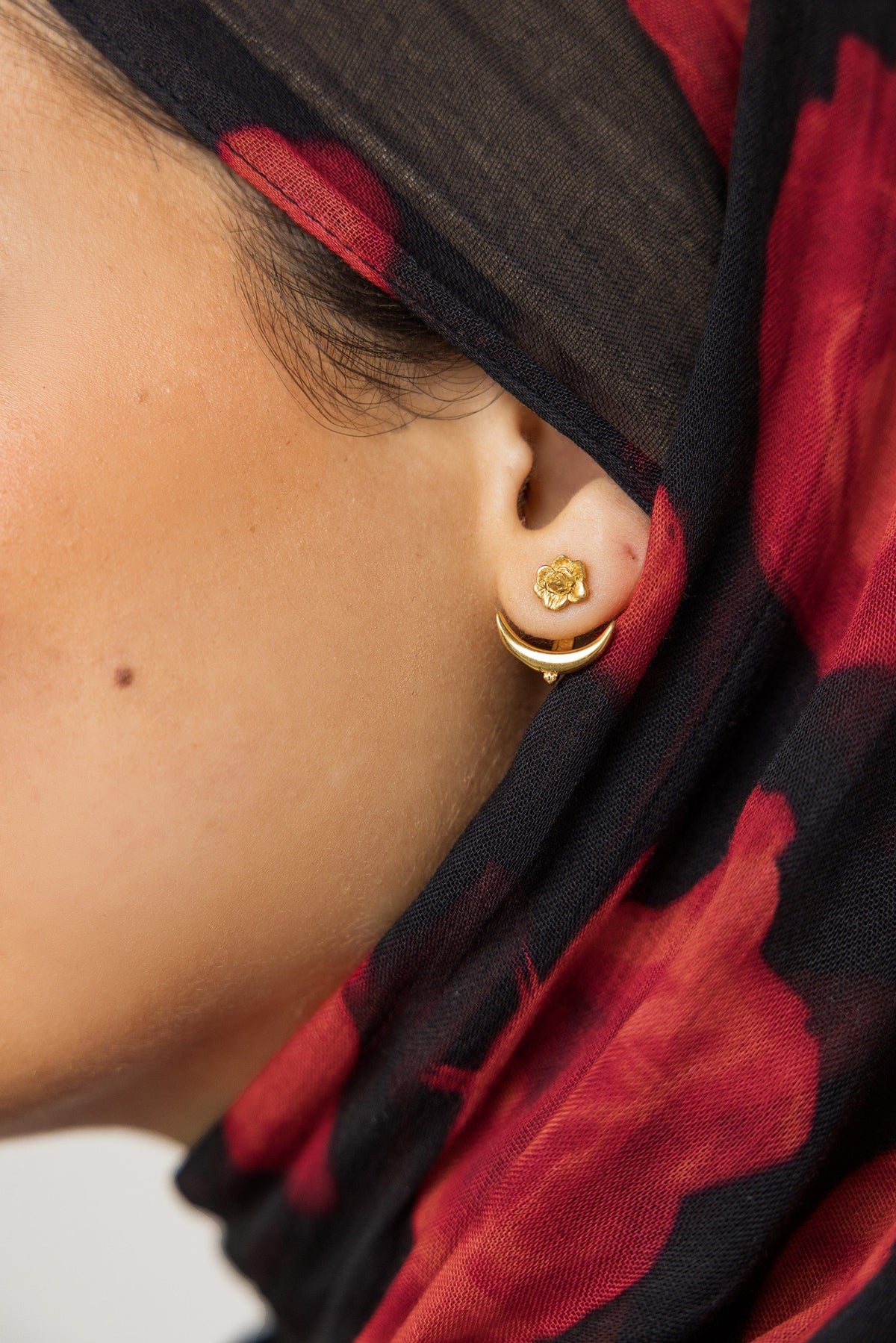 Close up of the gold Damask Rose & Crescent Jacket Earrings | VELA x Nominal as worn by the model on their left ear.