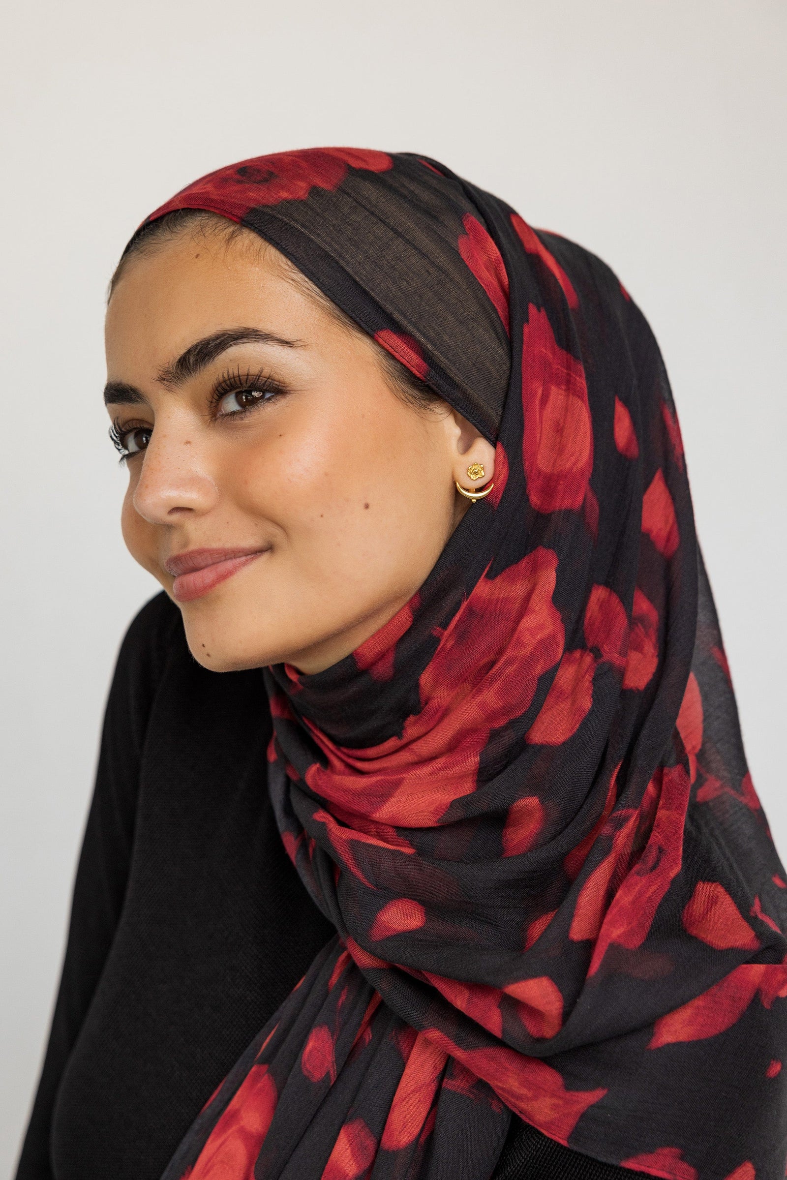 Photo of the model smiling. The model is wearing the Damask Rose & Crescent Jacket Earrings | VELA x Nominal on their left ear.