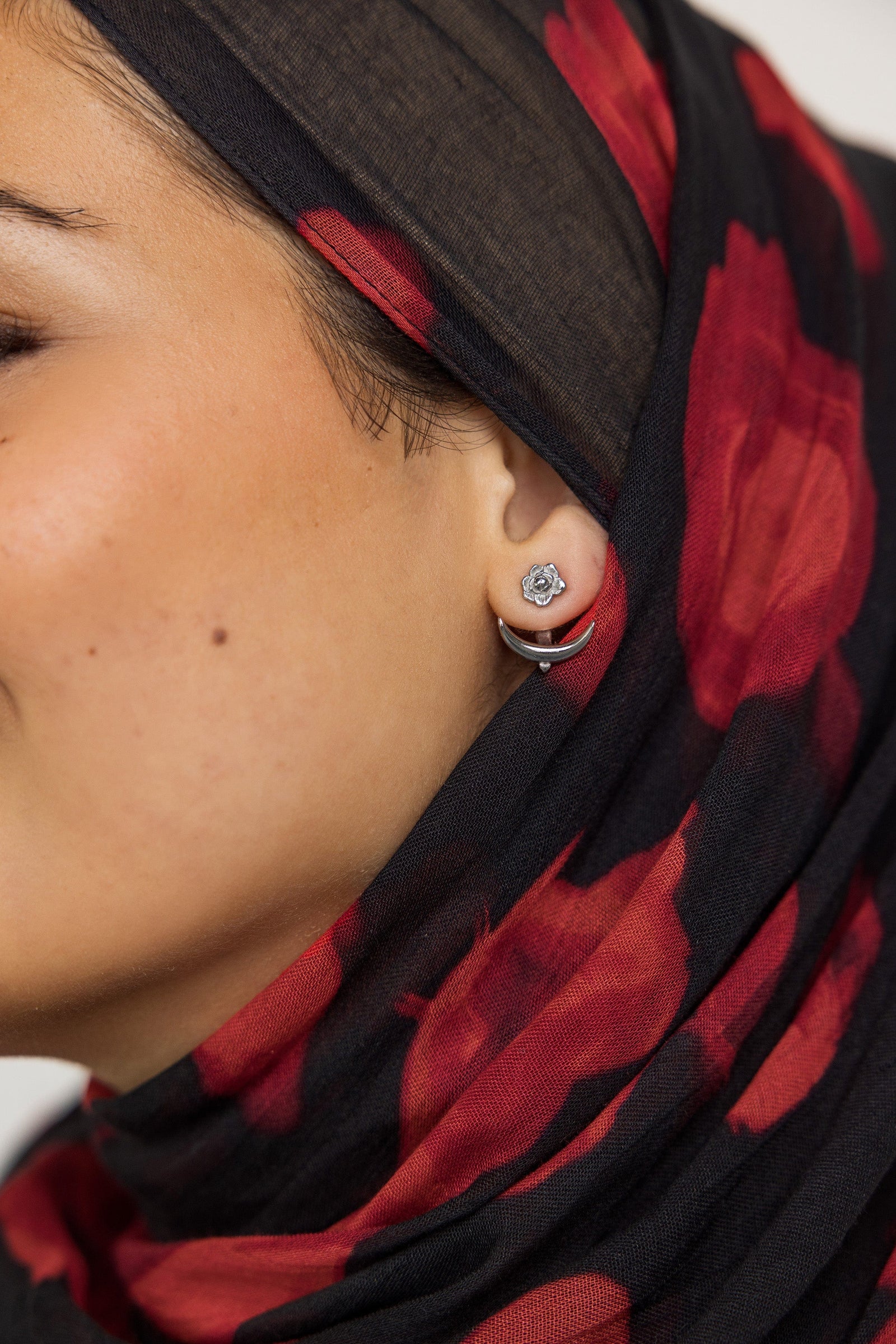 Close up of the silver Damask Rose & Crescent Jacket Earrings | VELA x Nominal as worn by the model on their left ear.
