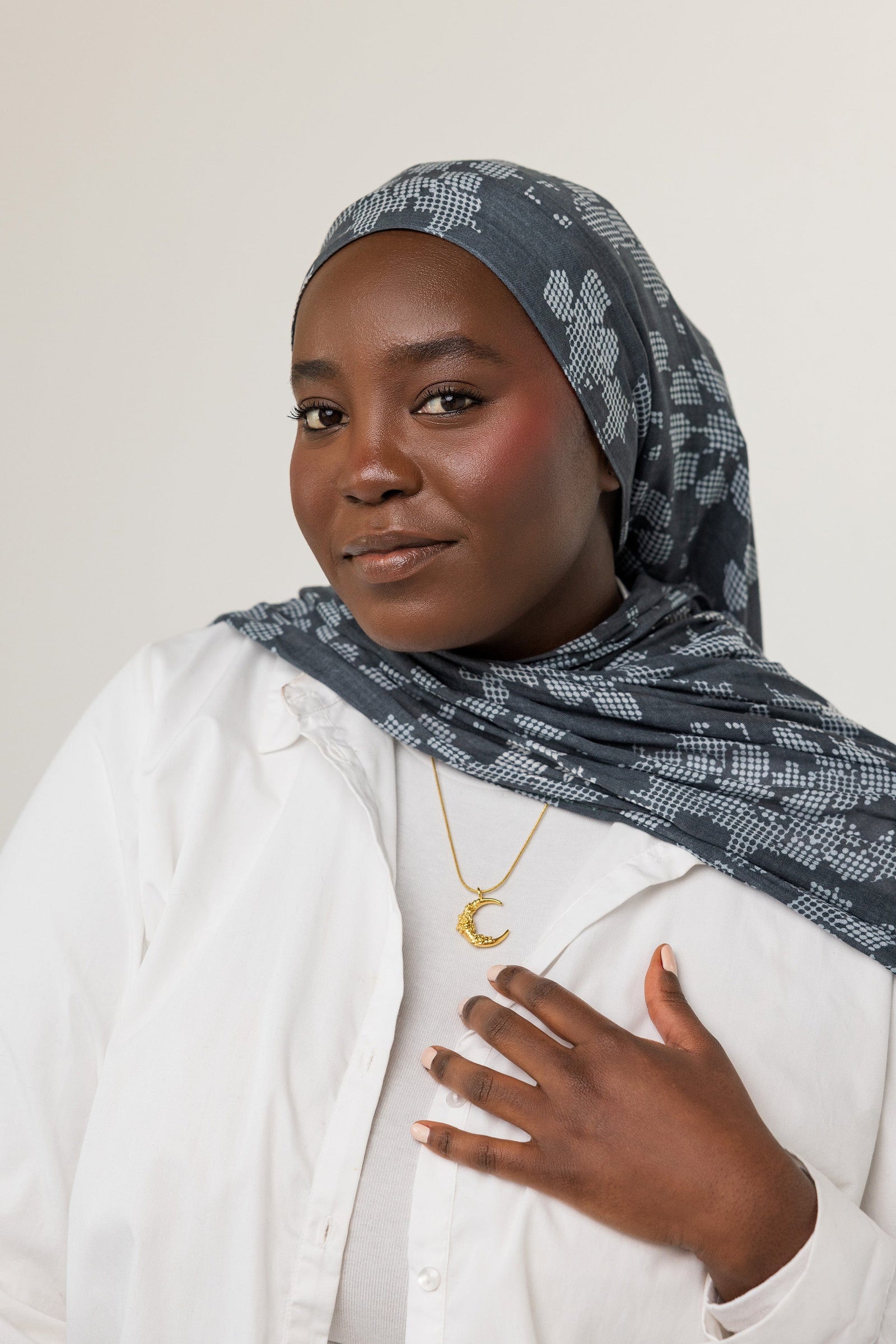 A model wearing the Damask Rose Crescent Necklace at its full 22-inch length. The necklace rests gracefully on the collarbone, highlighting the crescent moon pendant with rose detailing against a simple, neutral-toned outfit.