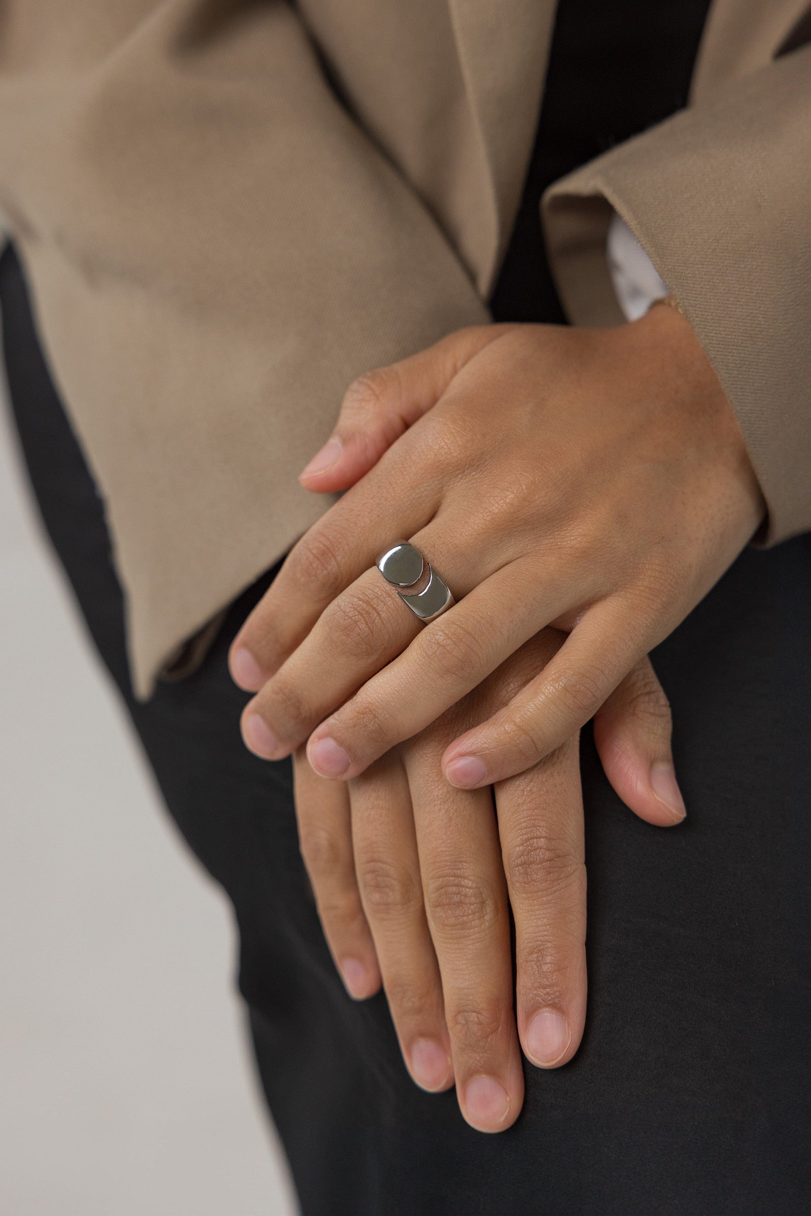 Woman wearing the Silver Phases Ring on her finger, styled with a tan blazer, hands relaxed and overlapping in front of her.