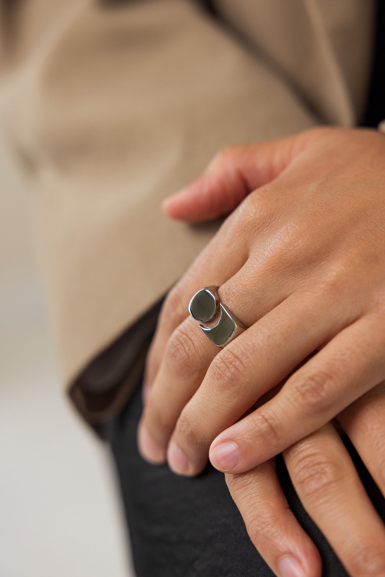 Woman wearing the Silver Phases Ring on her finger, styled with a tan blazer, hands relaxed and overlapping in front of her.